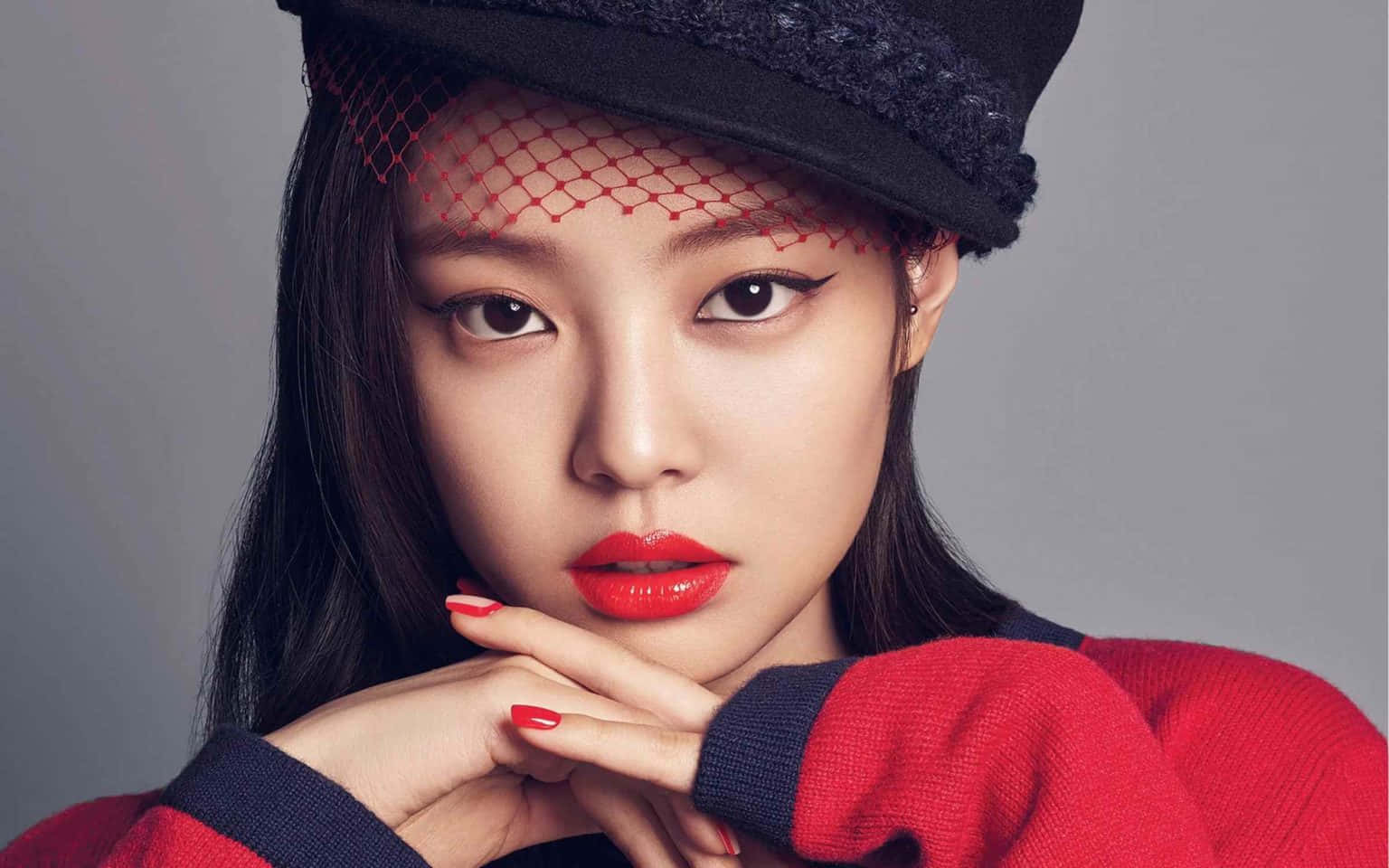Jennie Kim 黑紅造型酷照 壁紙 — 一位嘴唇鮮紅、戴著黑色紅網帽子的女士，雙手托腮，凝視著前方。