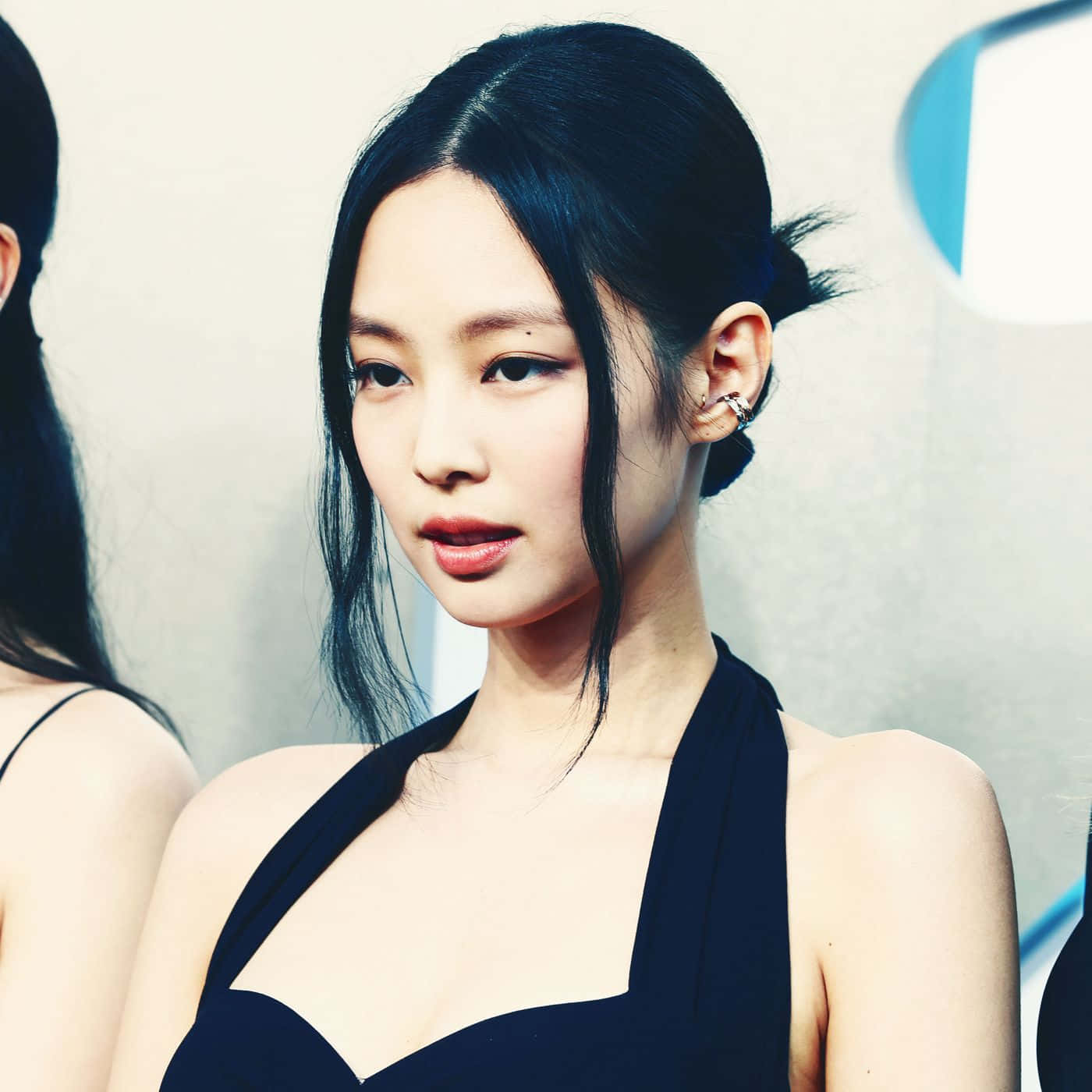 Jennie Kim 黑裙黑髮快照 壁紙 — 一位優雅的女人，擁有光滑的黑髮和鮮豔的紅唇，穿著時尚的黑色掛頸連衣裙，背景簡約。