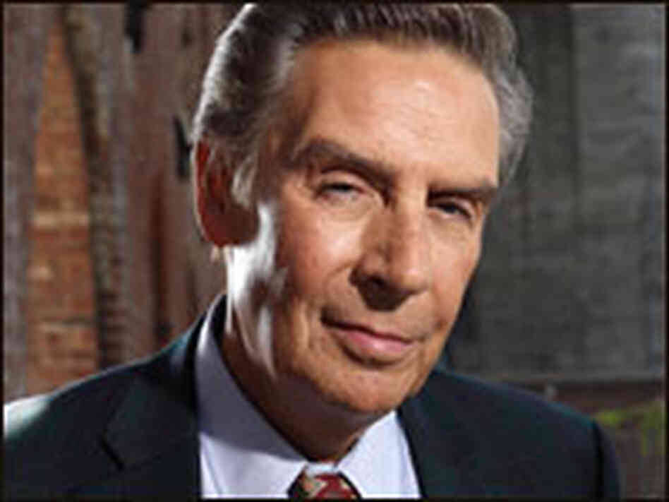 Jerry Orbach As Detective Lennie Briscoe Close Up Shot 壁紙 — 一位成熟男士的近距離肖像，身穿深色西裝和圖案領帶，在模糊的磚牆背景下溫柔微笑。