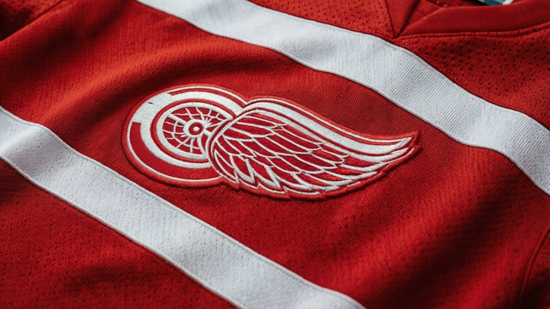 紅色冰球球衣，帶有白色條紋，胸前繡有翼輪標誌
