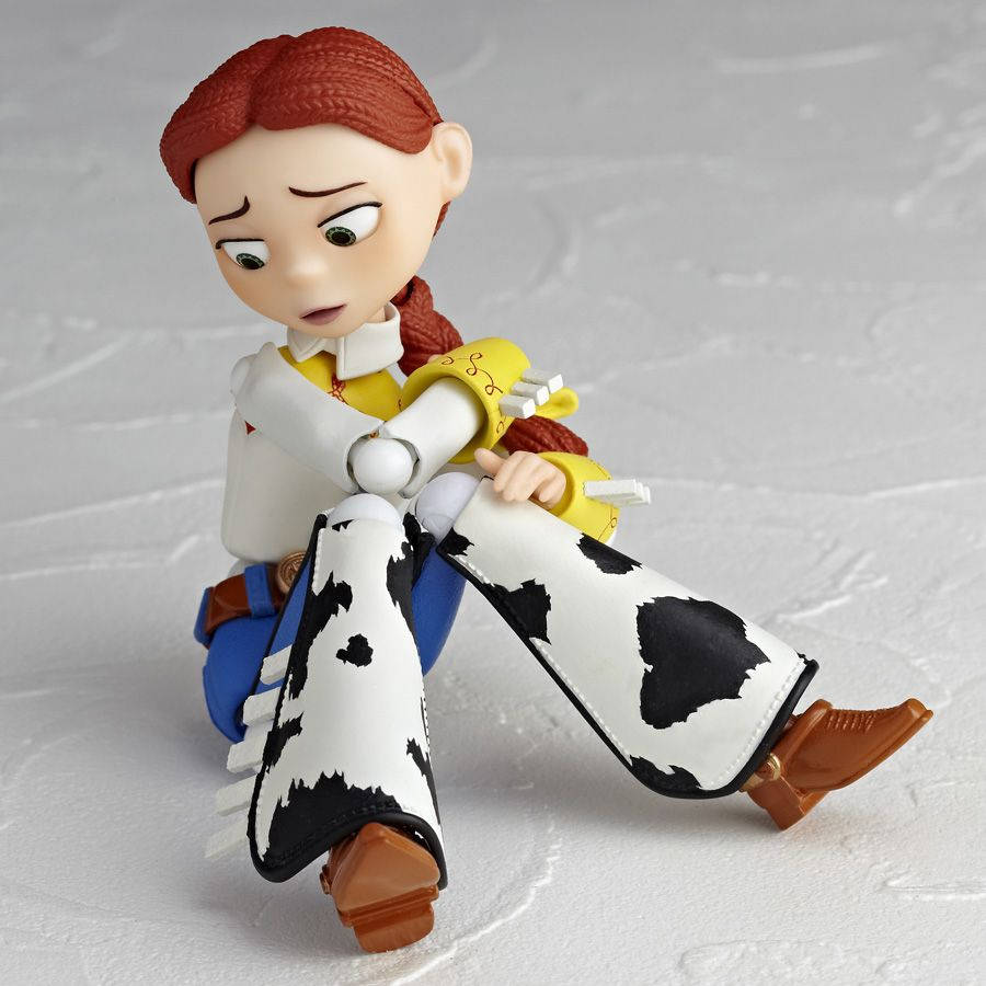 Jessie Toy Story 牛紋褲 壁紙 — 一個精細的《反斗奇兵》翠絲公仔盤腿坐在有紋理的白色表面上，表情若有所思。