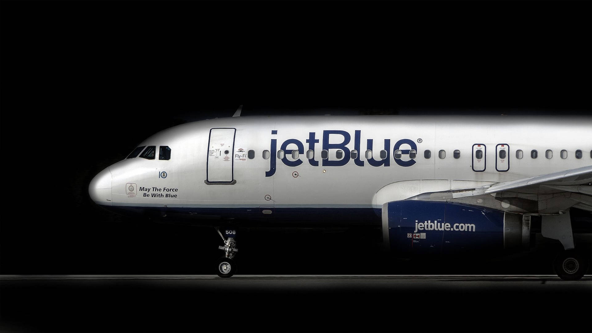 夜間在停機坪上亮起星際大戰標語的jetBlue飛機。