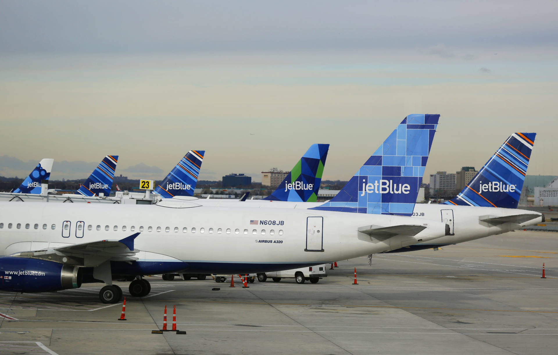 JetBlue飛機停泊在機場停機坪，背景為城市天際線。