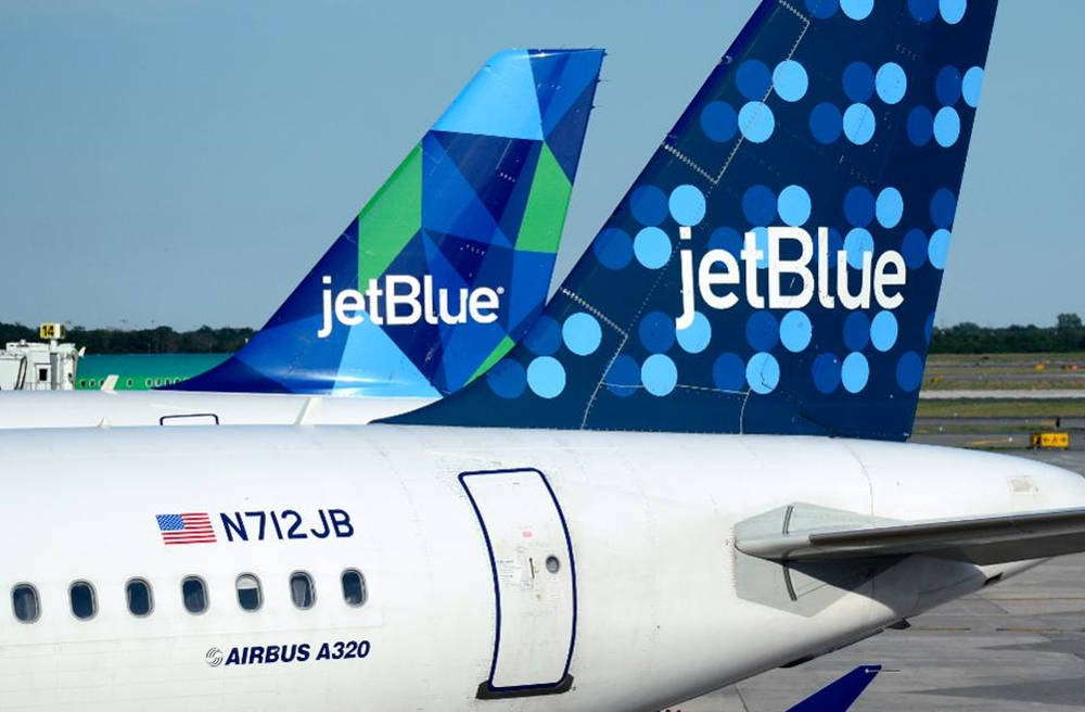 兩架 JetBlue 飛機停在機場停機坪上，展示其色彩繽紛的尾部。