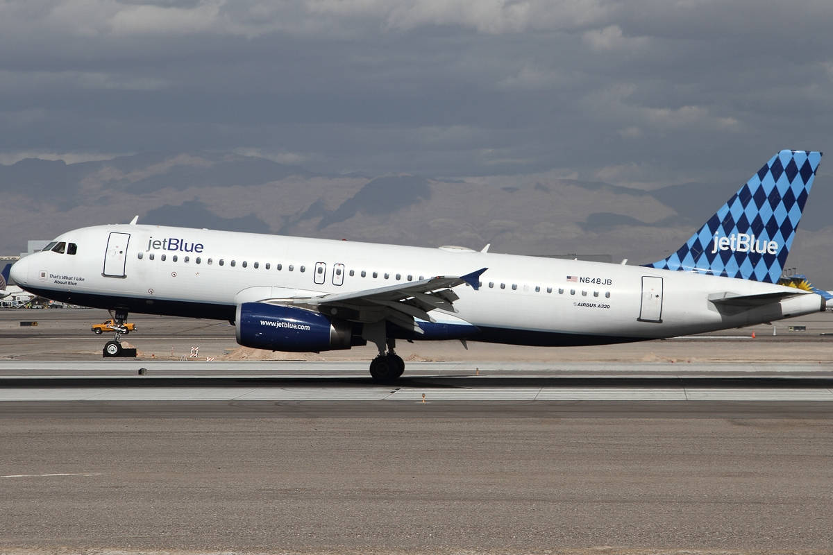 JetBlue 飛機在跑道上，背景有山脈，天空多雲
