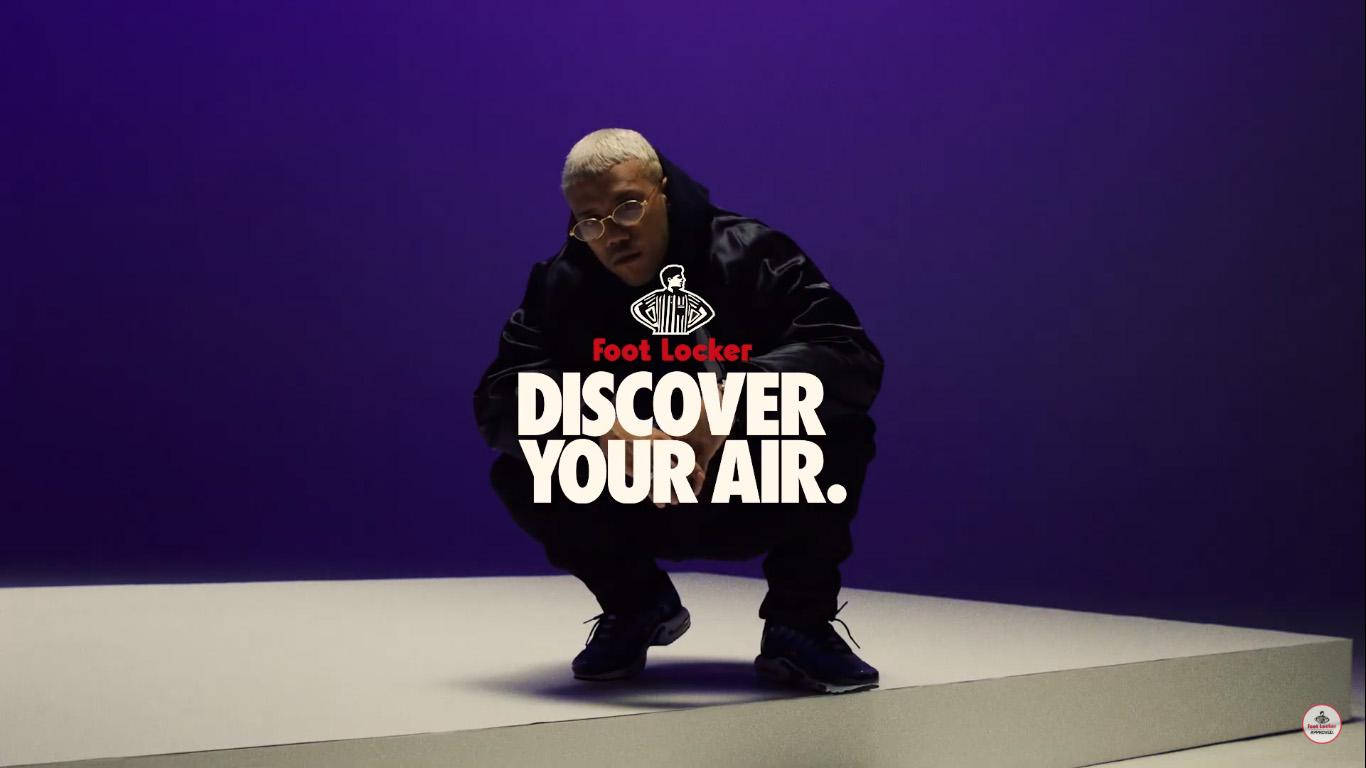 人物身穿黑色Foot Locker裝備蹲在紫色背景前，帶有「Discover Your Air」文字。