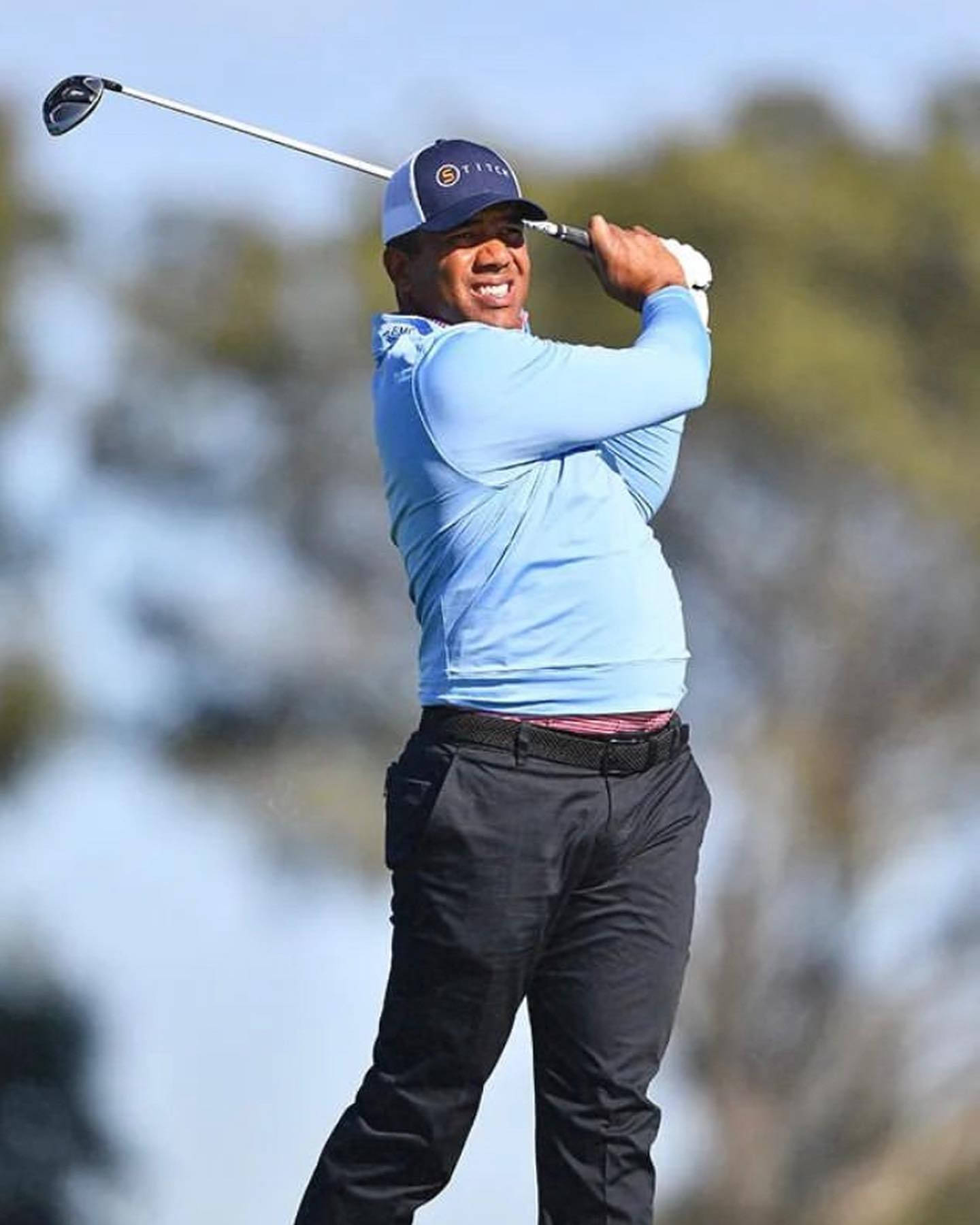 Jhonattan Vegas 強烈陽光下揮桿 壁紙 — 老虎活士在陽光明媚的高爾夫球場上揮桿，身後是模糊的綠色樹木。