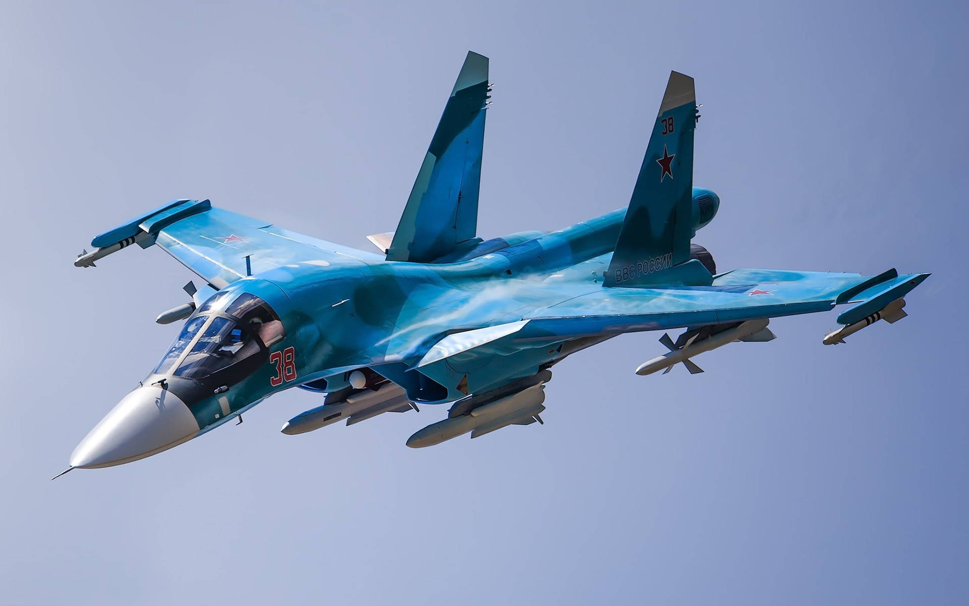 藍色軍用飛機在清澈的天空下飛行，機翼下掛載導彈