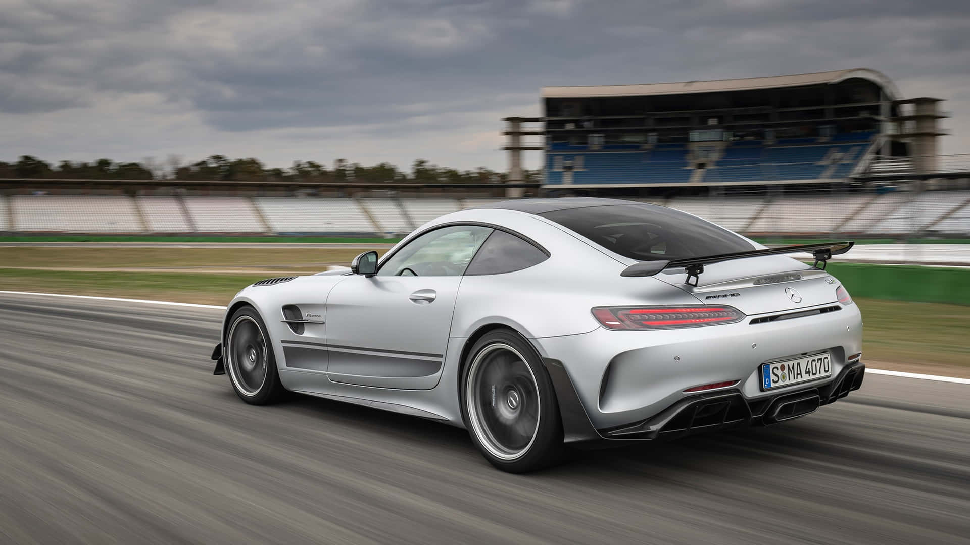  壁紙 — 一架銀色 Mercedes-AMG GT R 賽車在陰天之下，以模糊的動態沿著賽道飛馳。