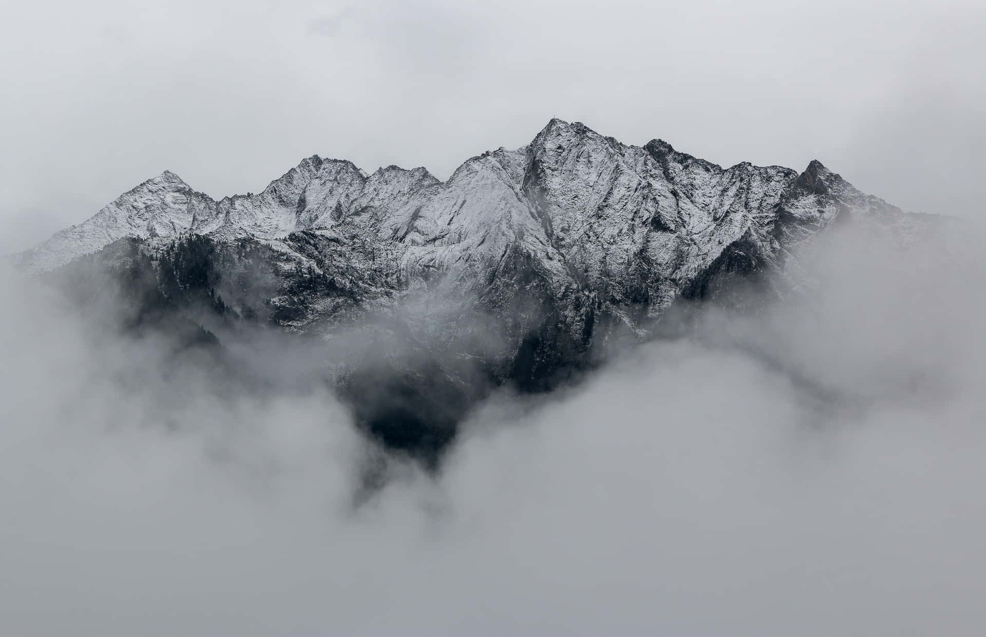 在陰天，積雪的山峰從濃密的雲層中浮現。