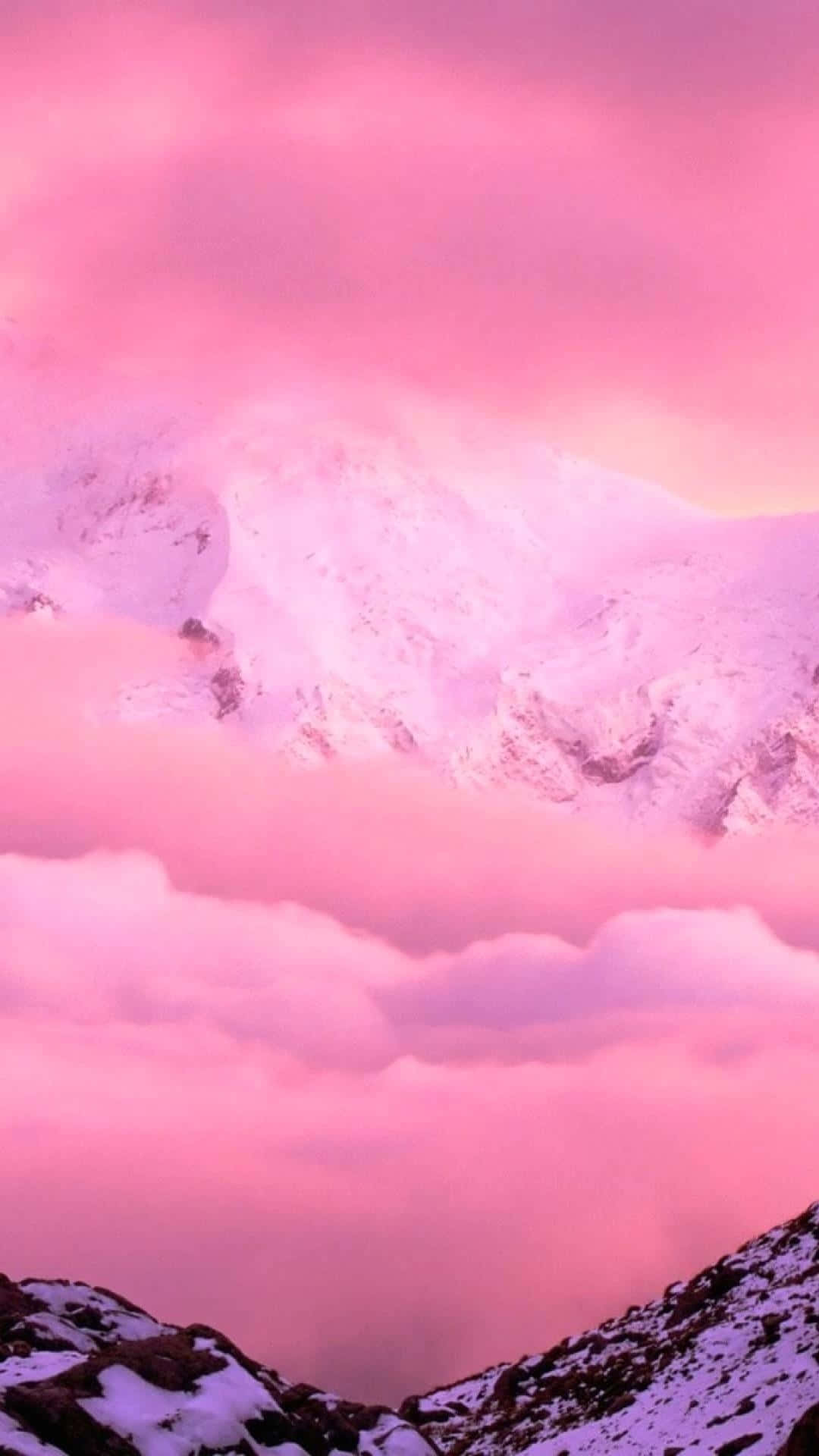  壁紙 — 積雪的山峰在夢幻般的暮色天空下穿過粉紅色的雲層。