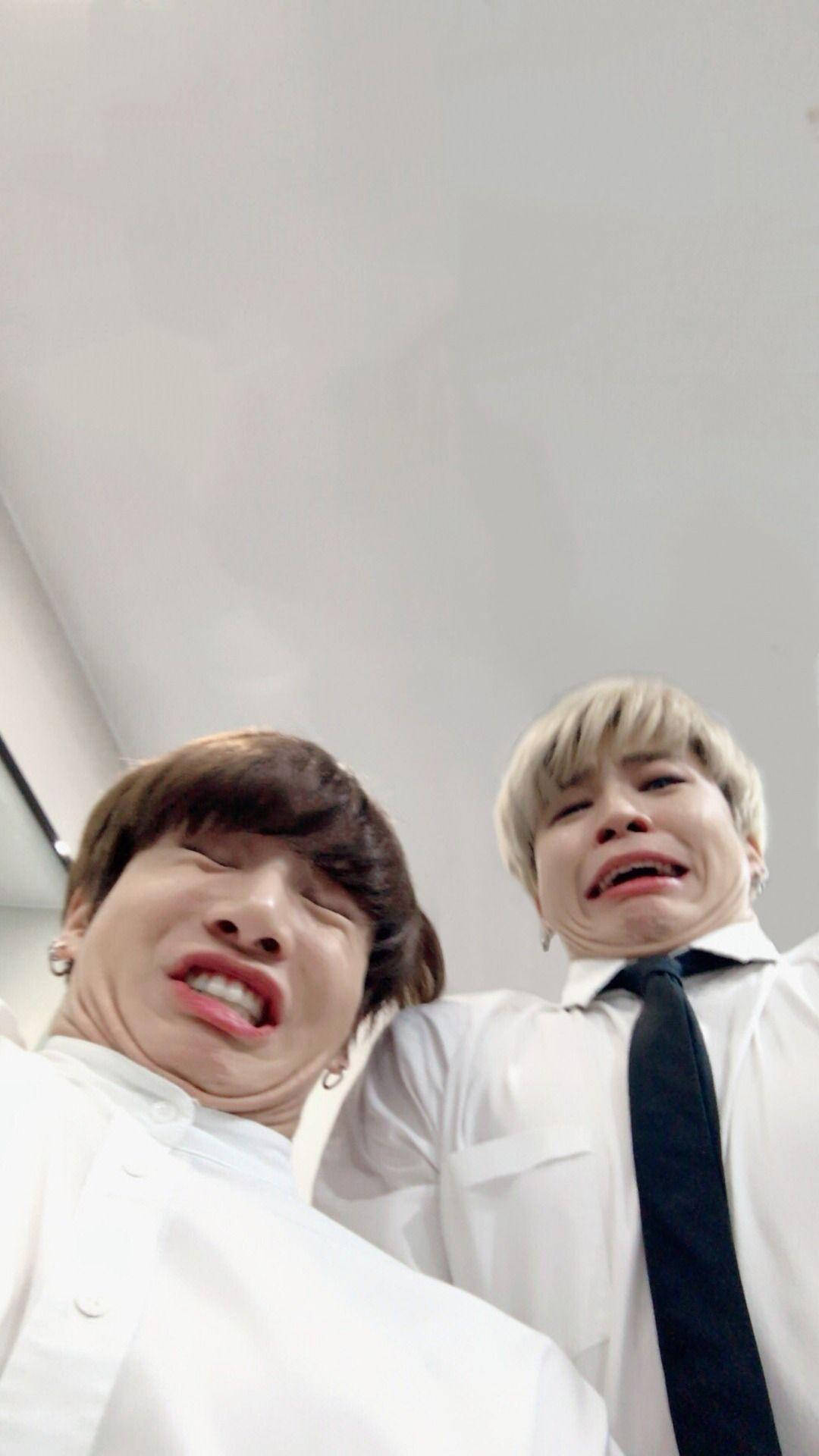 Jikook 穿黑領帶搞笑表情 壁紙 — 兩名身穿白恤衫的年輕男子在普通天花背景下，為近距離自拍做出誇張的傻臉。