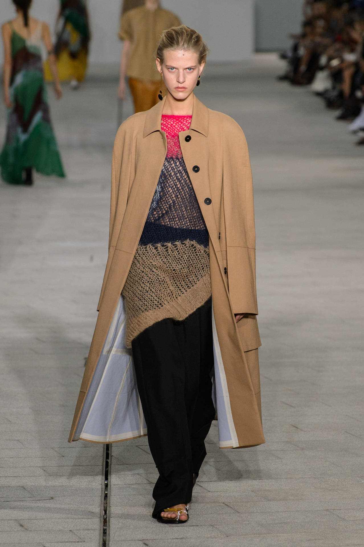 模特兒喺天橋上行catwalk，身穿層次感米色外套同黑色長褲。