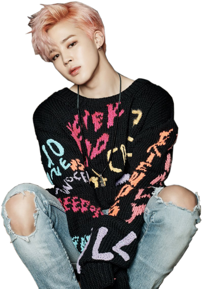 Jimin 粉髮時尚造型 壁紙 — 一位粉紅色頭髮的年輕男子穿著破洞牛仔褲和彩色針織毛衣，隨意地坐在黑色背景前。