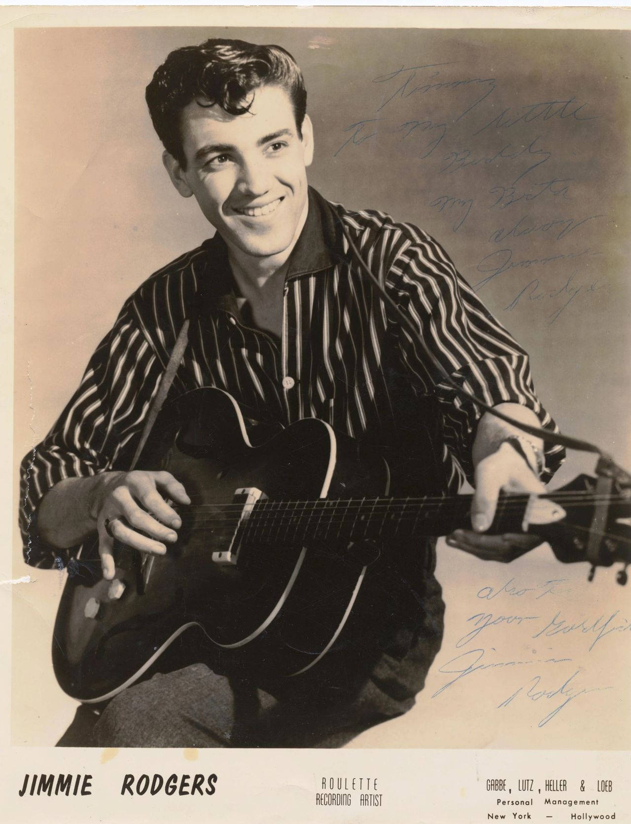 Jimmie Rodgers 經典海報 壁紙 — 微笑的Jimmie Rodgers身穿條紋襯衫，在帶有手寫簽名的復古工作室肖像中抱著一把原聲結他。