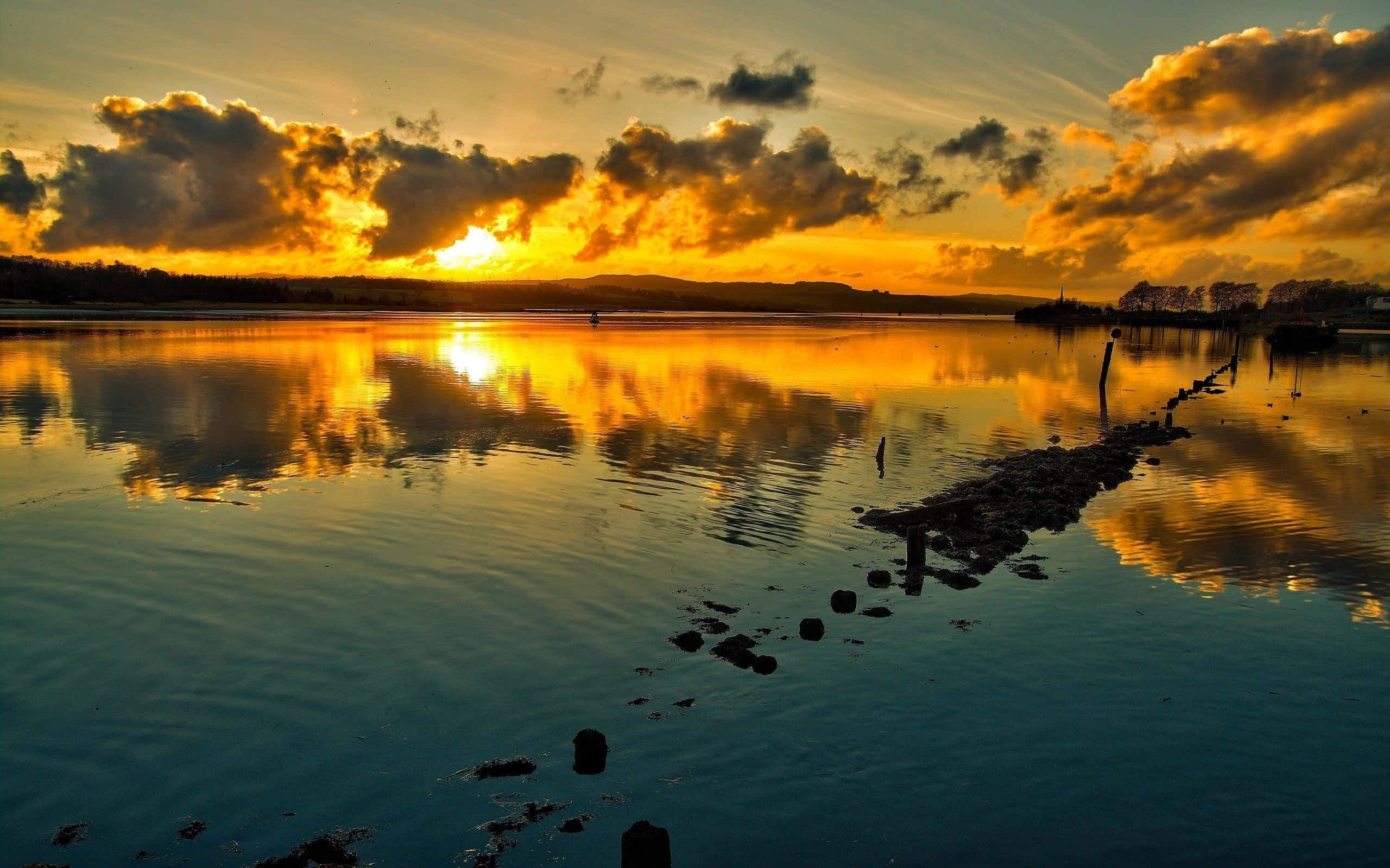 Sunset Reflection 桌布 壁紙 — 金色夕陽在寧靜的湖面上投射出熾熱的倒影，一條石碼頭延伸到平靜的水面。