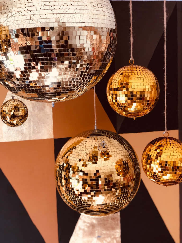  壁紙 — 金色 disco 球懸掛在黑色和陶土色的幾何圖案牆上。