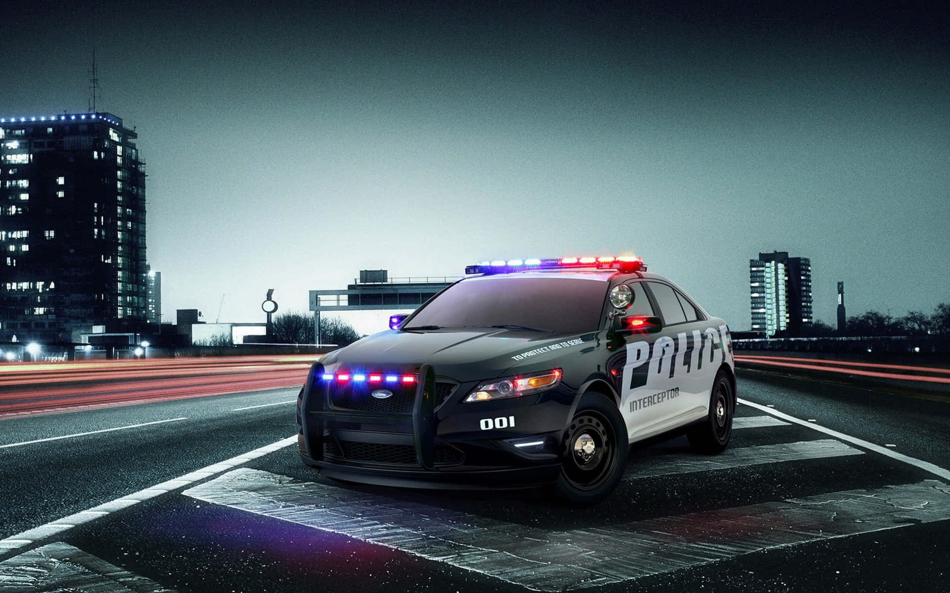 Ford Taurus 桌布 壁紙 — 一輛黑白警車閃爍著紅藍燈光，在雨夜的城市中疾馳，留下模糊的動態軌跡。