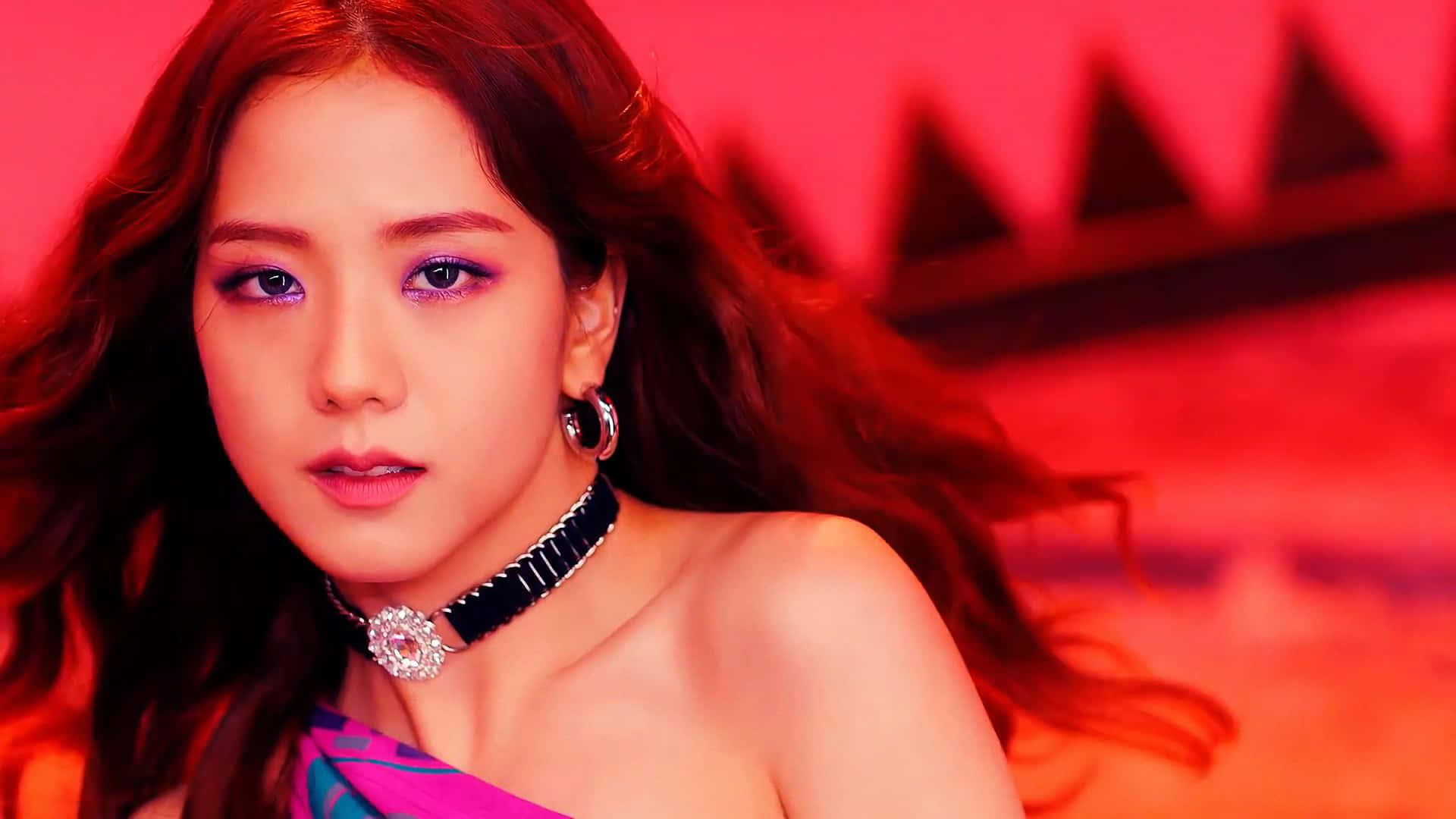 Jisoo BLACKPINK《Kill This Love》造型 壁紙 — 一位擁有飄逸長髮和濃妝豔抹的女性，在帶有幾何陰影的鮮紅色背景下凝視著。