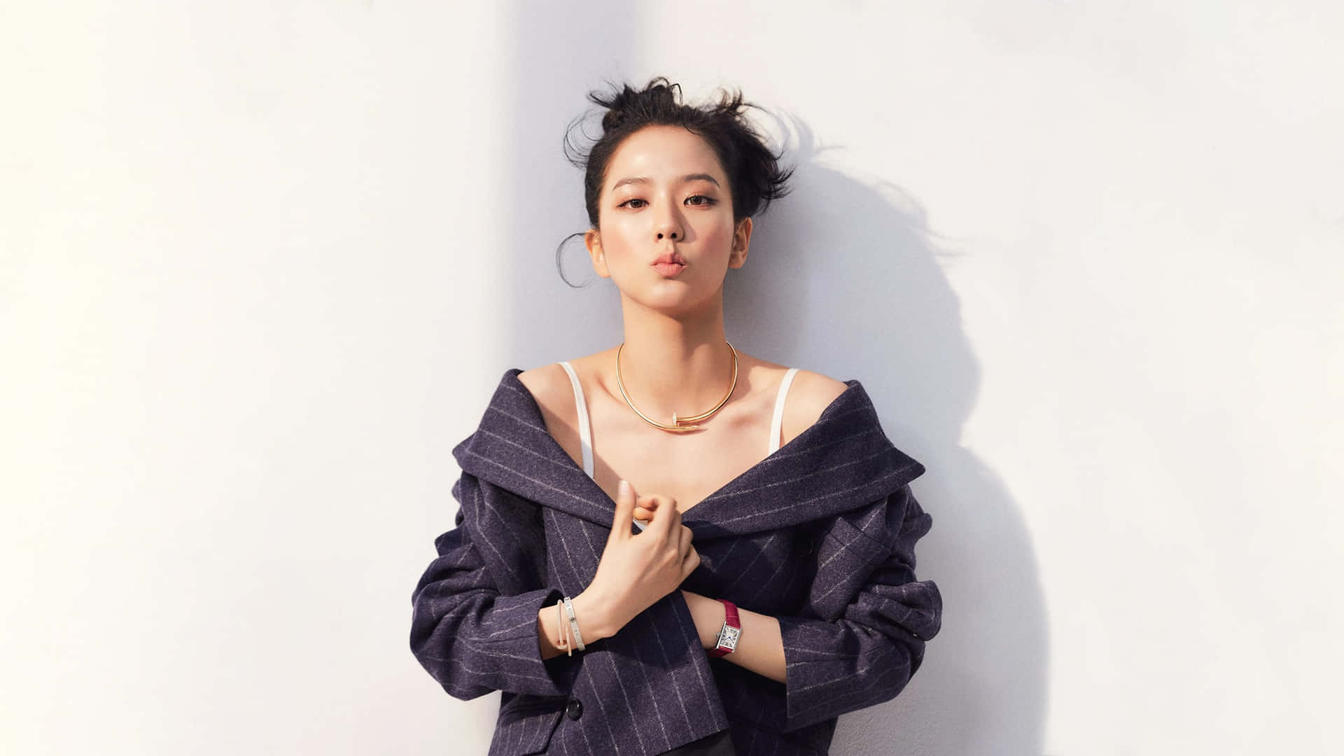 身穿細條紋西裝外套的女性靠著白牆做出嘟嘴表情