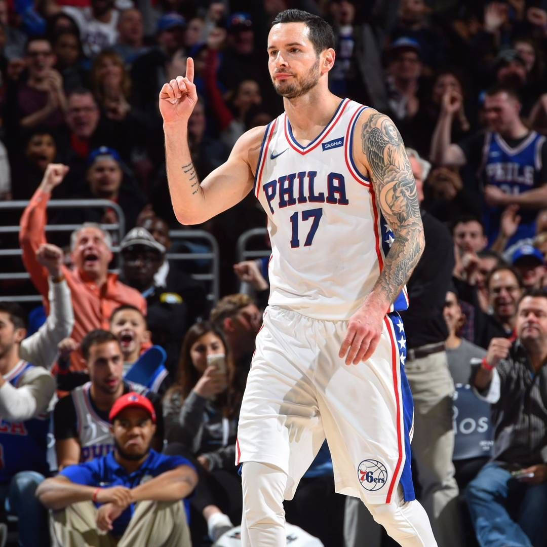 Jj Redick 勝利瞬間 壁紙 — 一位身穿白色17號球衣的費城76人籃球運動員在激烈的比賽中豎起一根手指向上示意，背景是歡呼的球迷。