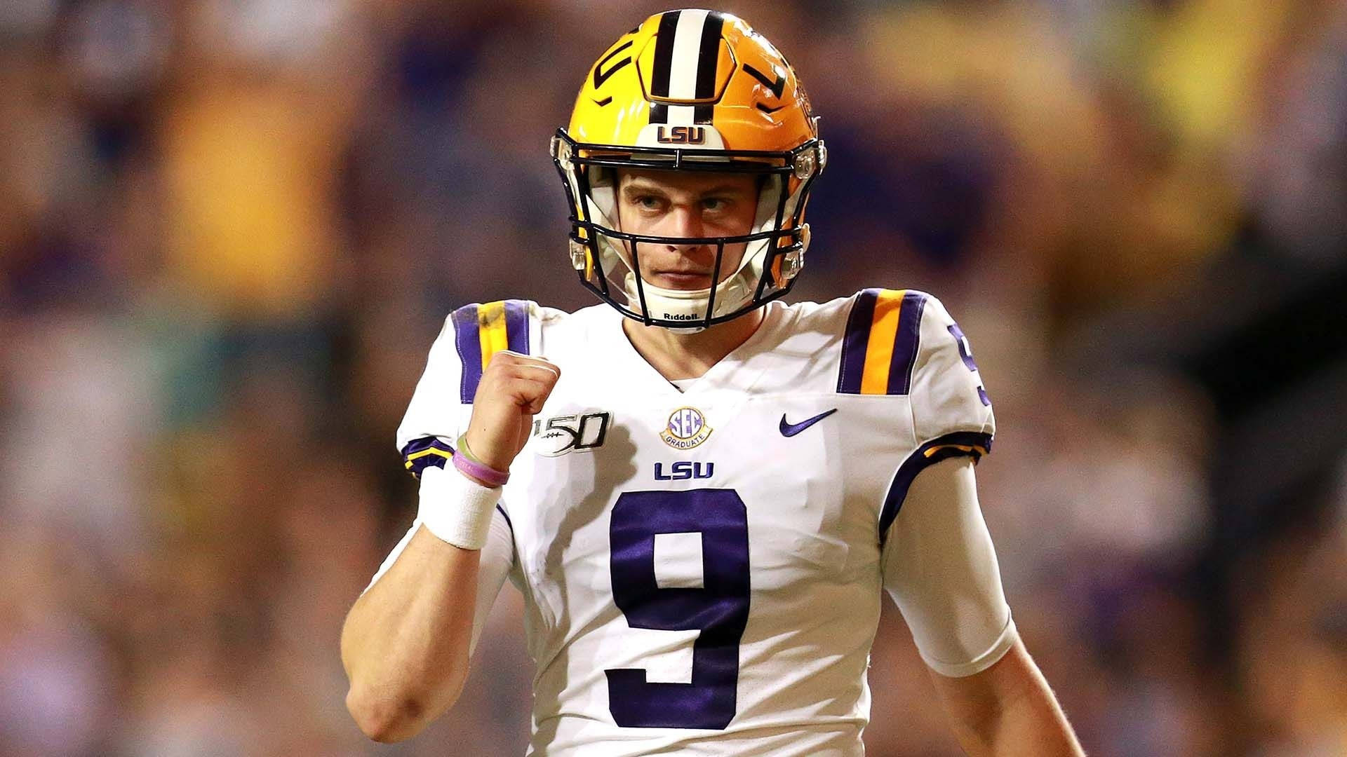 Joe Burrow 滿意神情 壁紙 — 一位專注的LSU美式足球四分衛身穿白色和紫色球衣，在體育場燈光下高舉拳頭慶祝勝利。