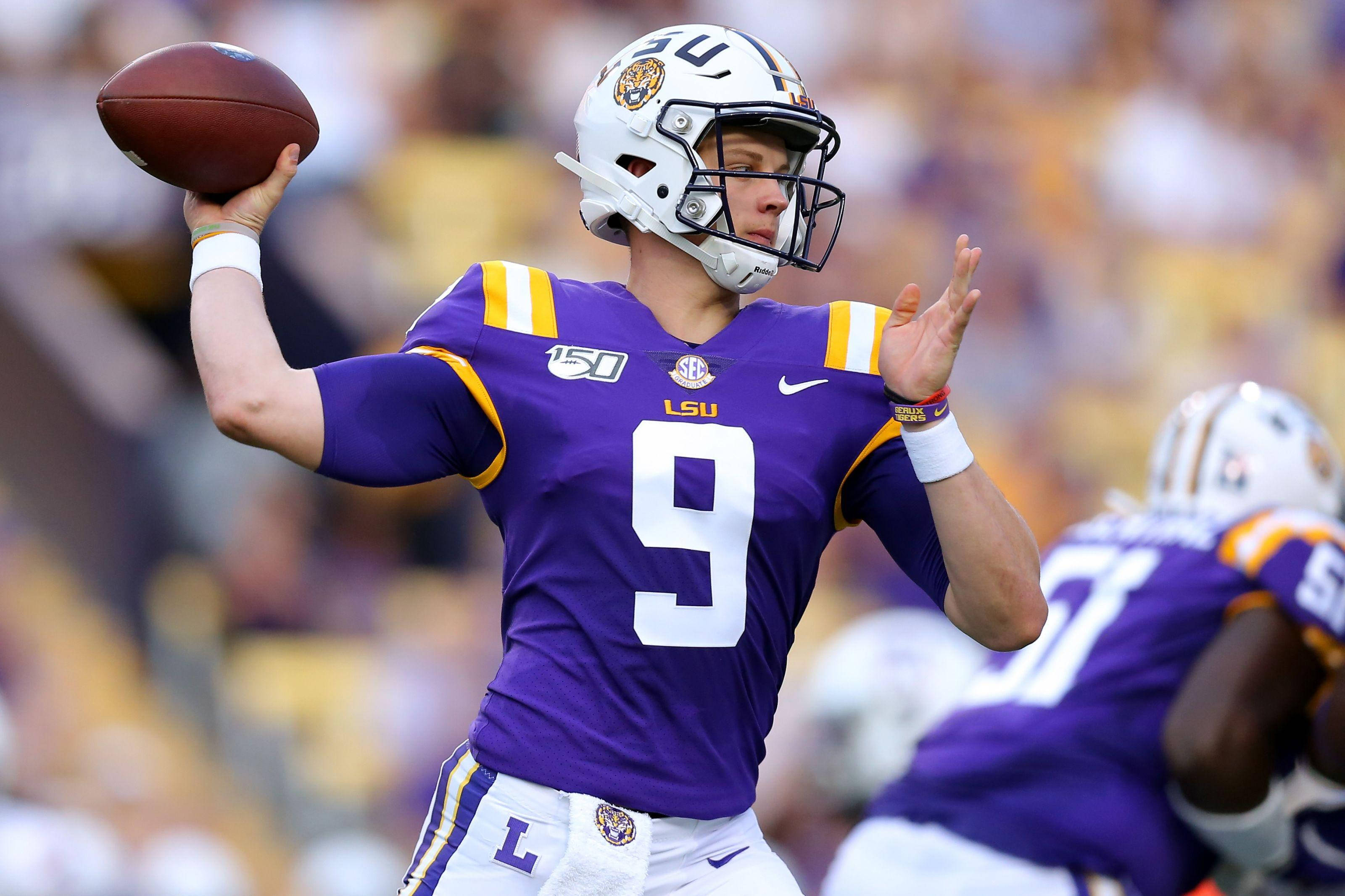 Joe Burrow投球姿勢 壁紙 — LSU 美式足球四分衛 9 號身穿紫色球衣，在日間比賽中準備投球。