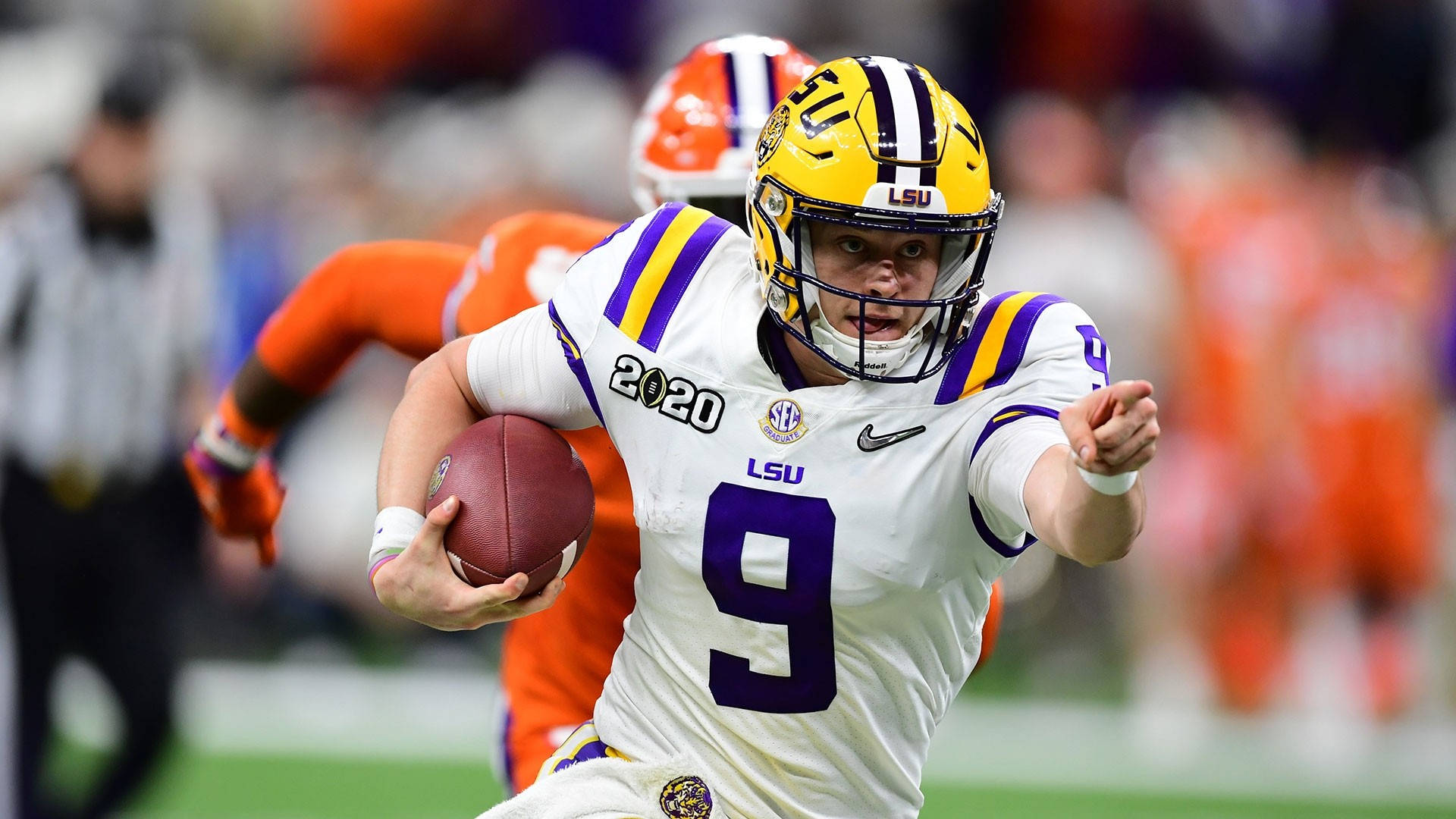 Joe Burrow賽場指揮 壁紙 — LSU 美式足球四分衛9號身穿白色、紫色和金色球衣在比賽中帶球奔跑。
