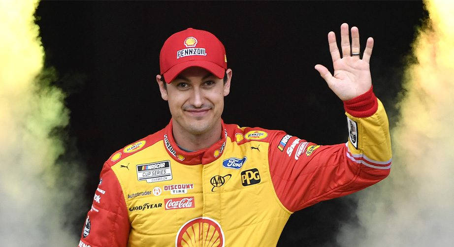 NASCAR車手在黃色煙霧中揮手，賽車服上有贊助商標誌。