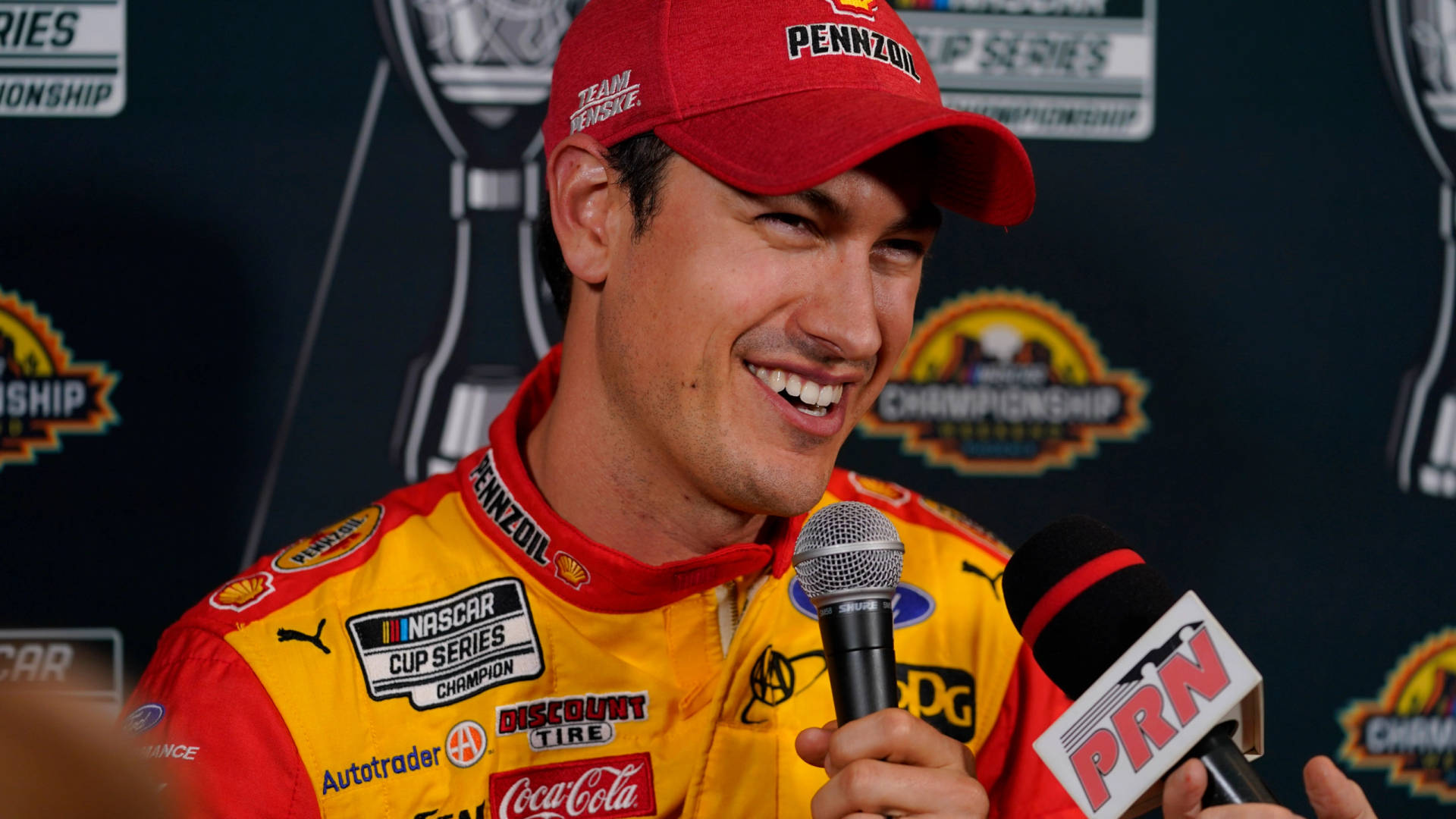 NASCAR車手在記者會上微笑，面前有麥克風。