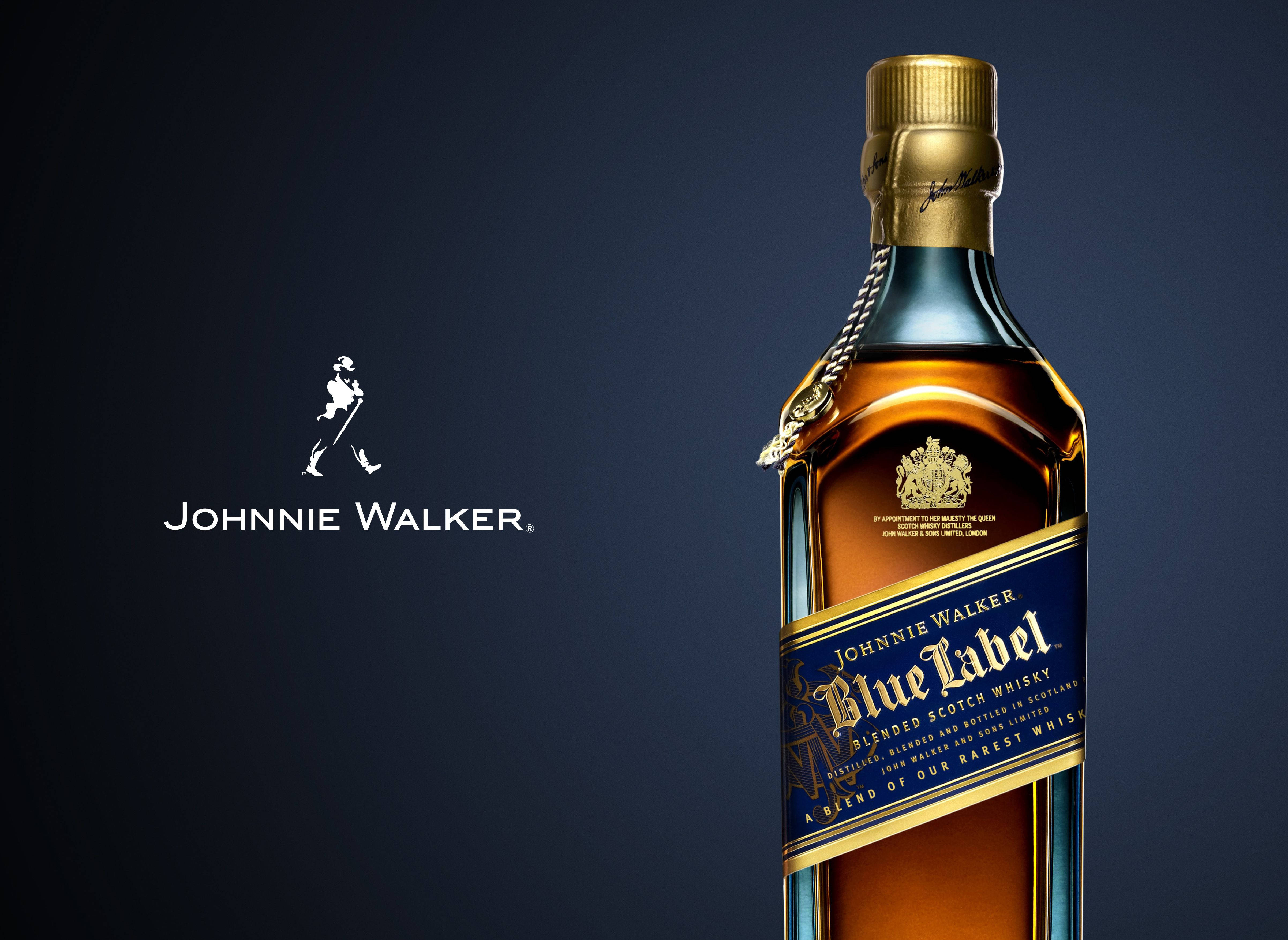 Johnnie Walker Blue Label — 精英品味的象徵 壁紙 — 一瓶時尚的約翰走路藍牌威士忌在深色漸變背景上閃耀，旁邊是標誌性的標誌。