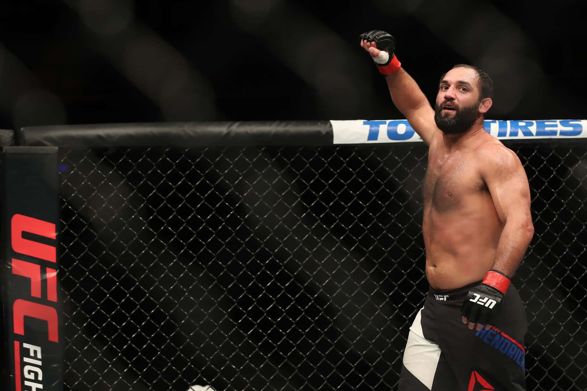 UFC拳手在八角籠內高舉拳頭慶祝勝利。