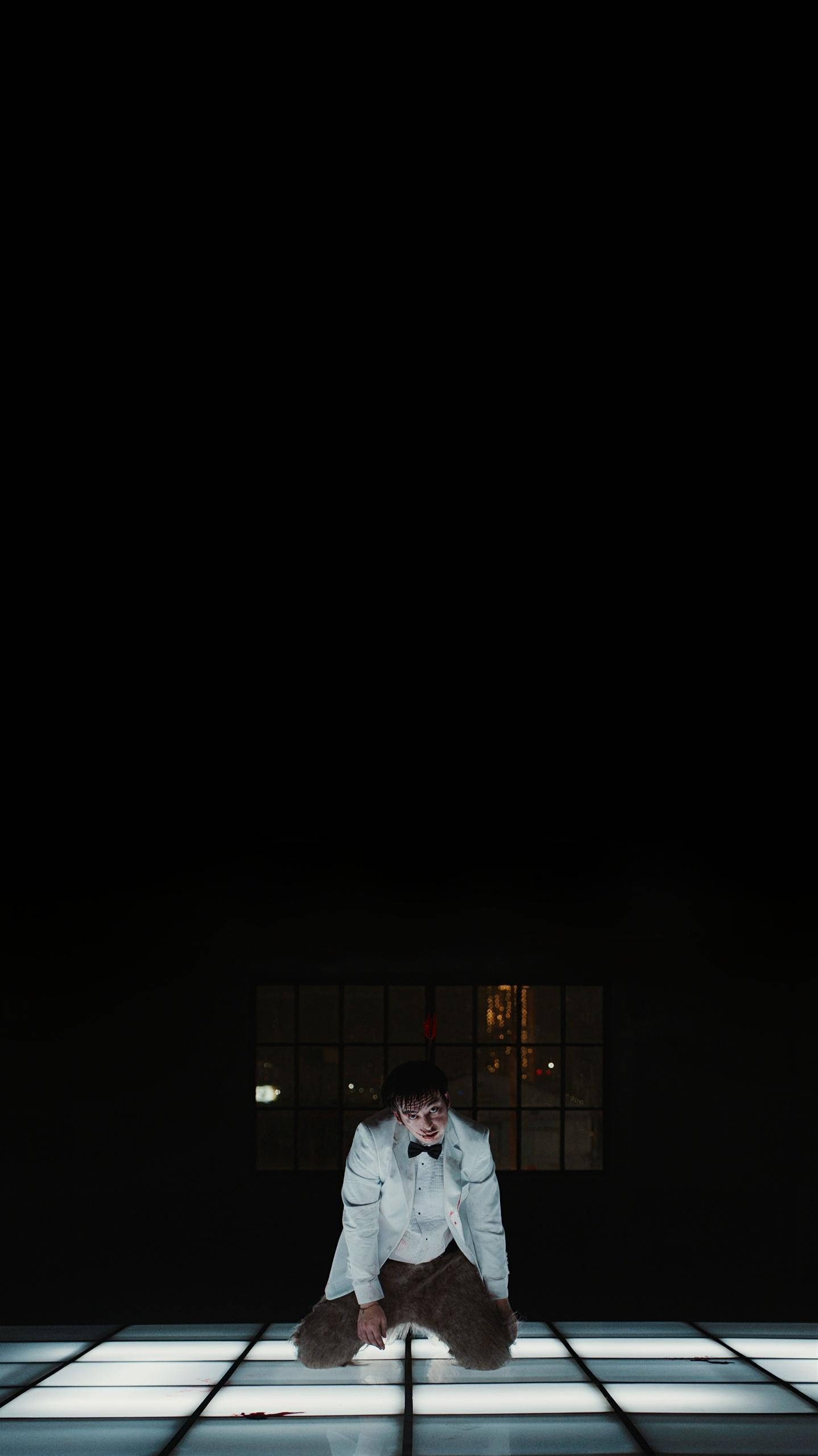 Joji 跪地海報 壁紙 — 一個穿著白色西裝的人跪在黑暗房間中發光的網格地板上，身後有一扇窗戶。