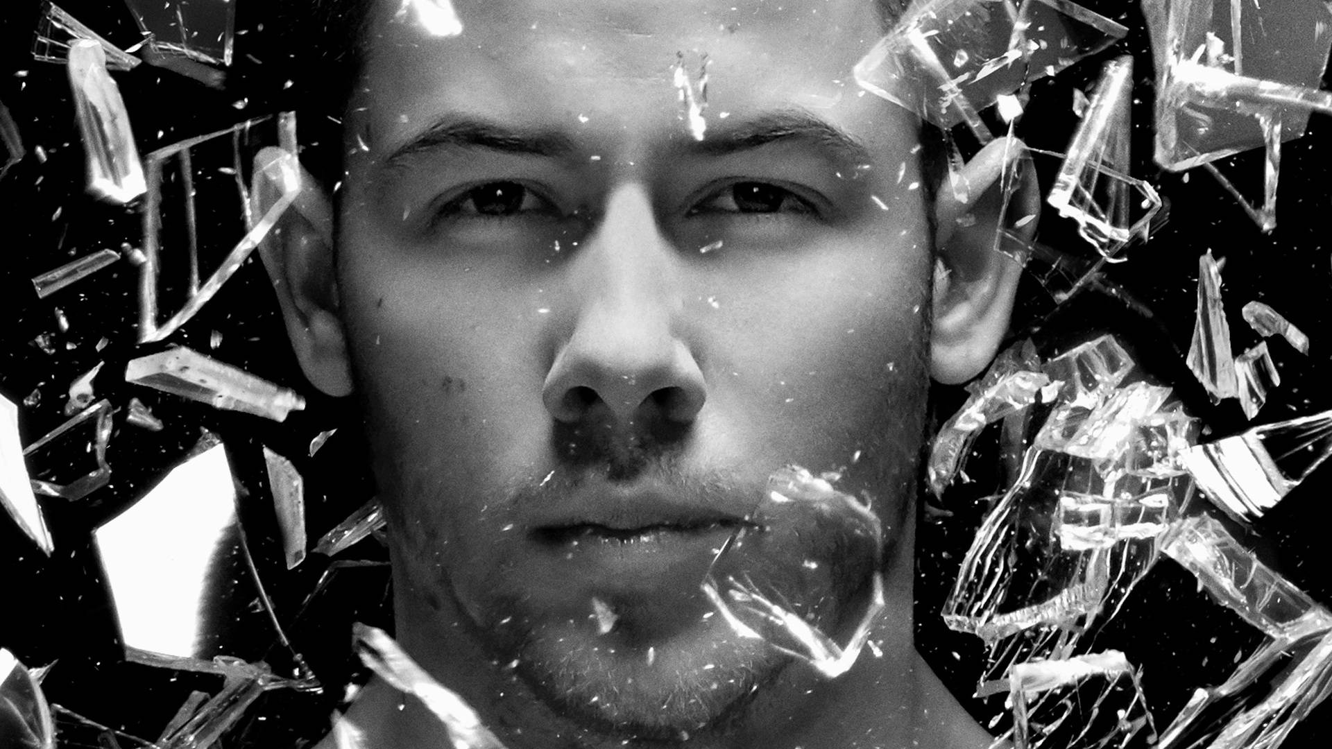 Jonas Brothers的Nick Jonas《Last Year Was Complicated》專輯海報 壁紙 — 一個男人強烈的面孔從破碎的玻璃碎片中浮現，高對比度的黑白肖像。