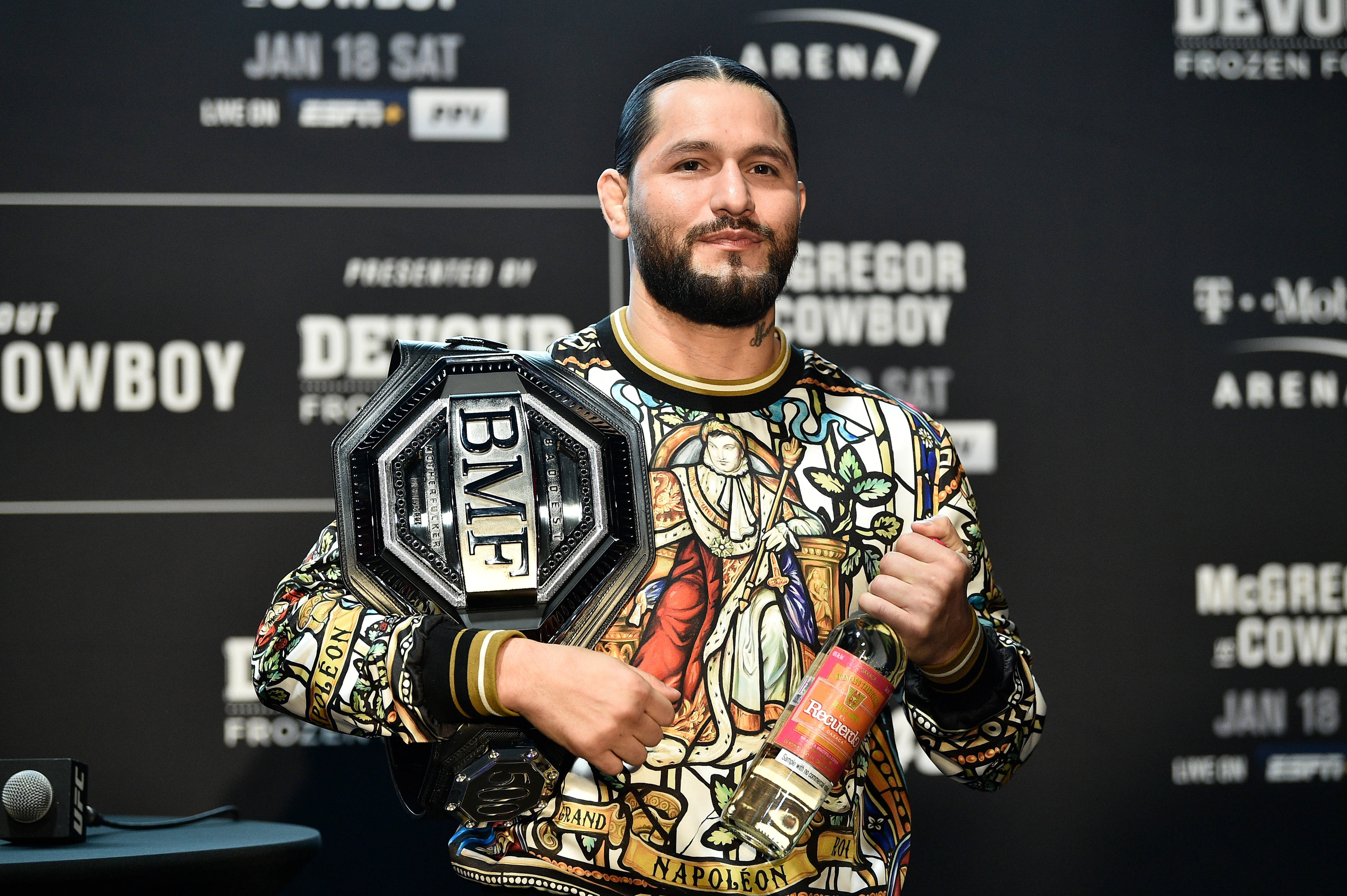 Jorge Masvidal 拿著冠軍腰帶 壁紙 — 一名身穿彩色圖案襯衫的拳手在記者會上手持BMF冠軍腰帶和一瓶拿破崙威士忌。