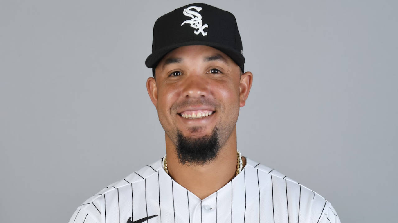 Jose Abreu 微笑 壁紙 — 一位面帶微笑的棒球運動員身穿芝加哥白襪隊制服，在純灰色攝影棚背景前擺姿勢。