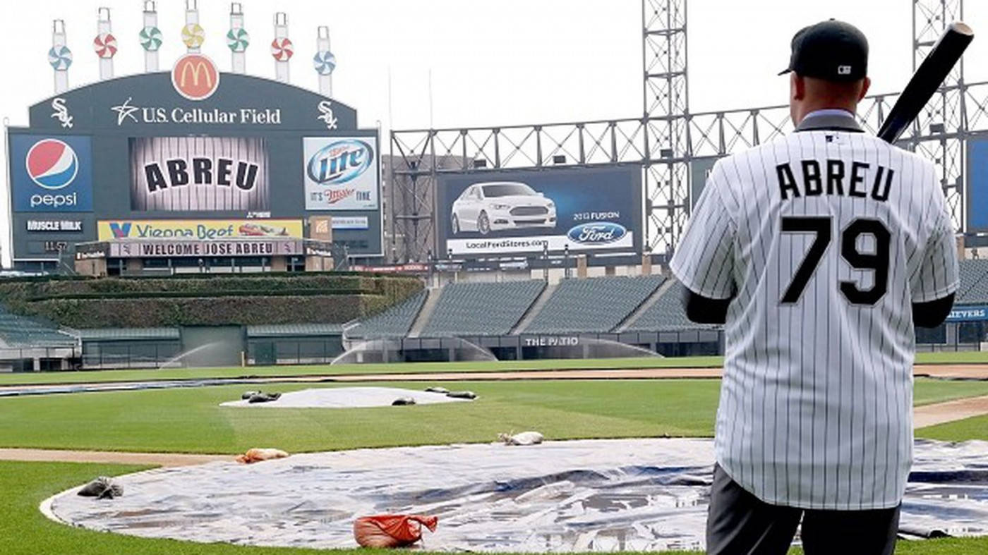 Jose Abreu 球場觀賽 壁紙 — 一名身穿條紋球衣的棒球運動員站在U.S. Cellular Field的有蓋場地上，身後是球場廣告和空座位。