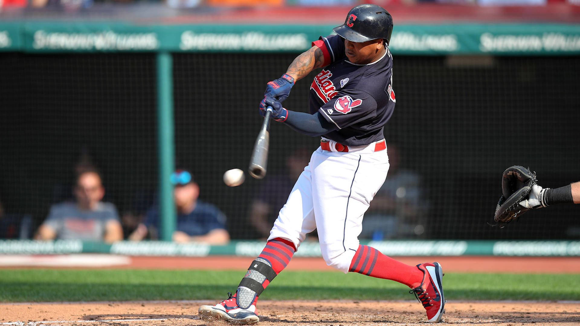 Jose Ramirez 擊球瞬間 壁紙 — 一名身穿深色球衣的棒球手在日間比賽中揮棒擊球，背景有觀眾。