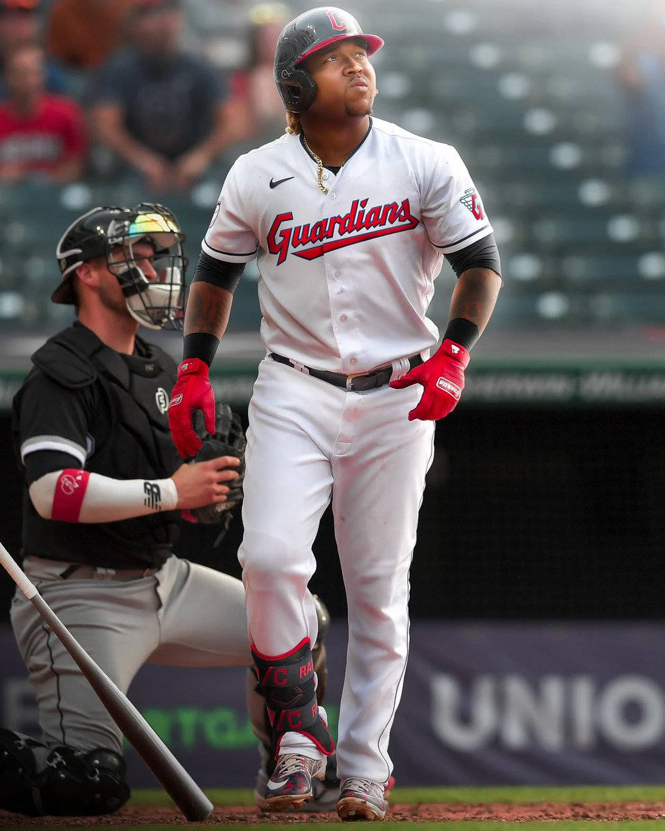 Jose Ramirez 白色球衣 壁紙 — 一名身穿守護者隊球衣的棒球選手在本壘板前，身後有捕手和裁判。
