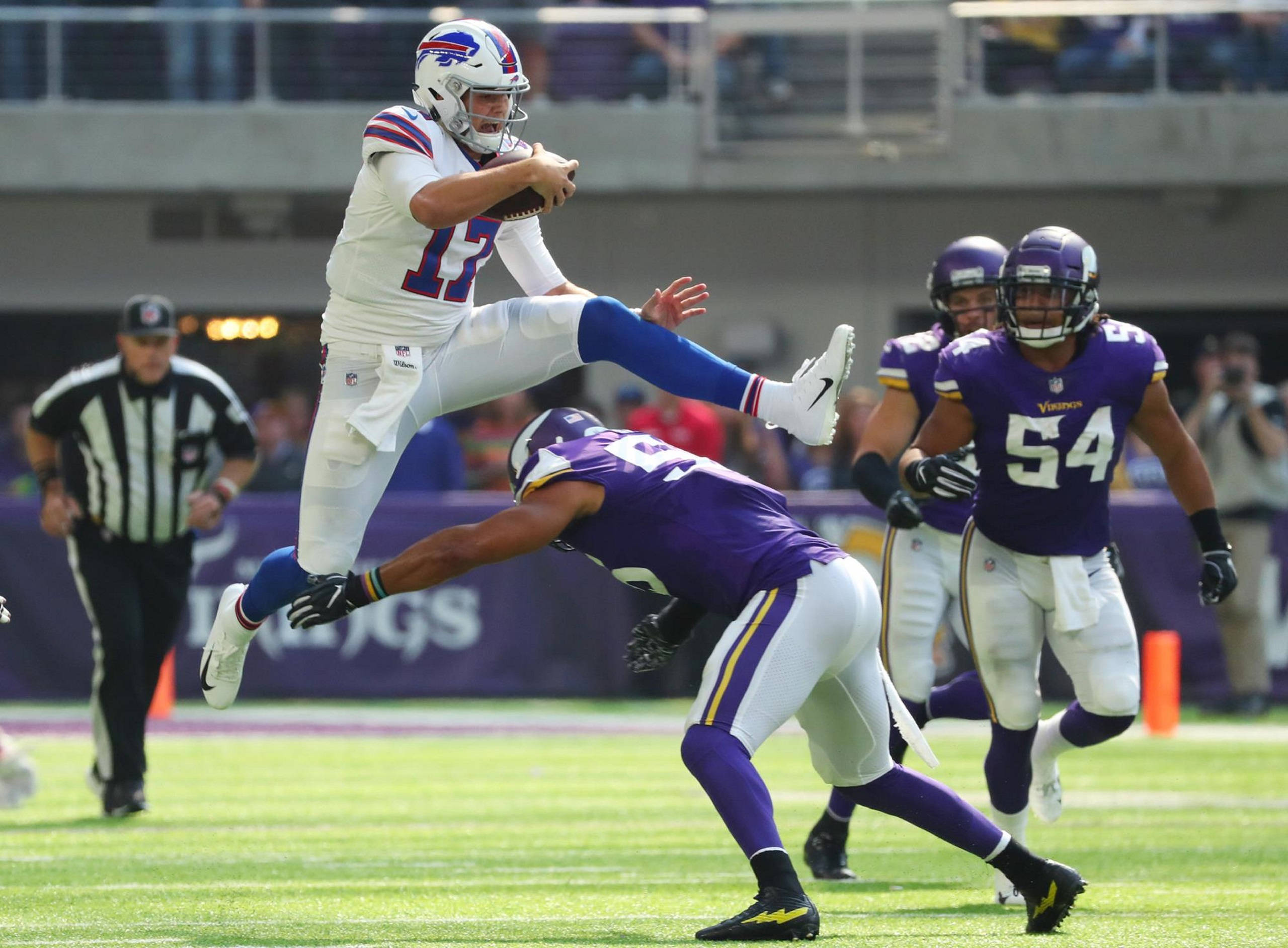 Josh Allen 對戰明尼蘇達維京人隊 壁紙 — 水牛城比爾的四分衛在激烈的NFL比賽中跳過明尼蘇達維京人隊飛撲的防守球員。