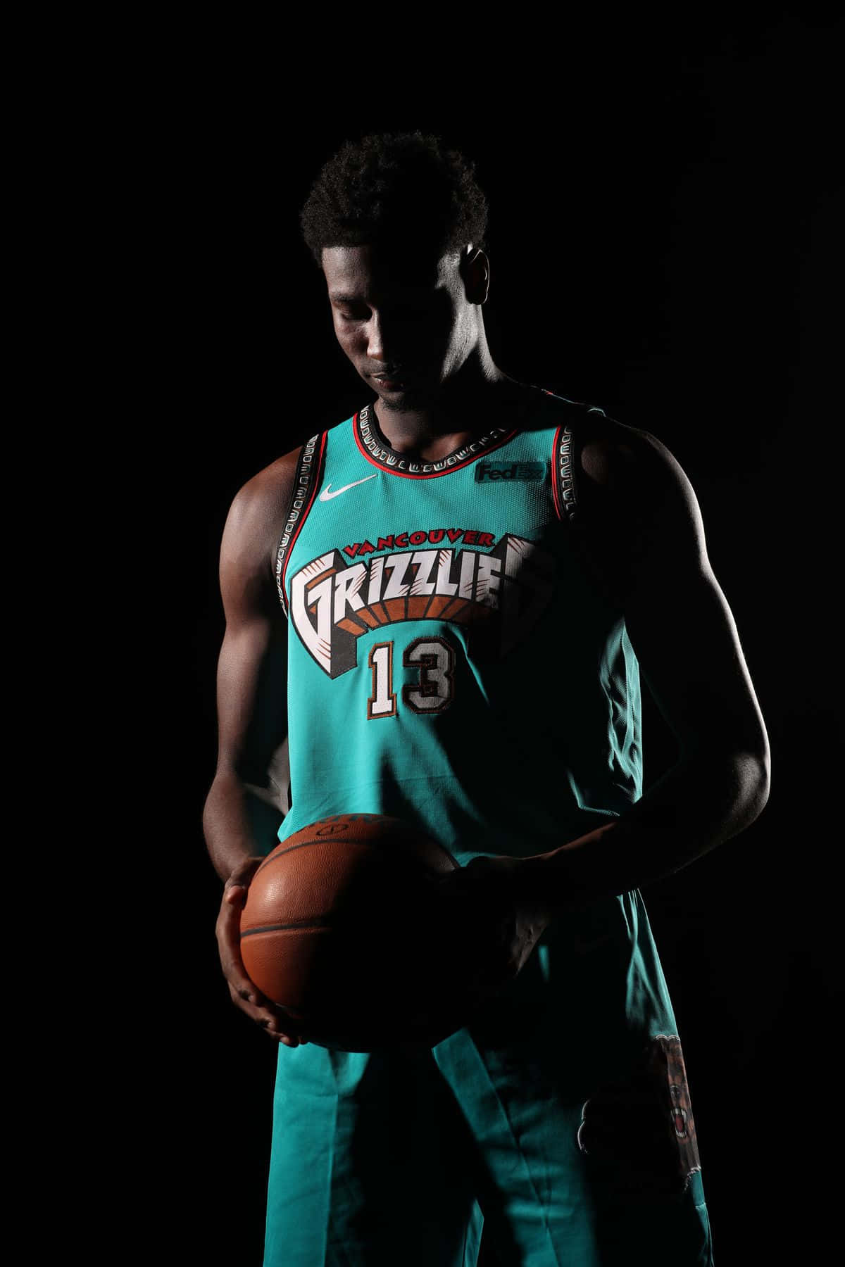 賈倫·傑克遜 Jr. 2019 NBA媒體日 壁紙 — 一名身穿青綠色溫哥華灰熊隊球衣的籃球運動員，在黑色背景和戲劇性燈光下持球。