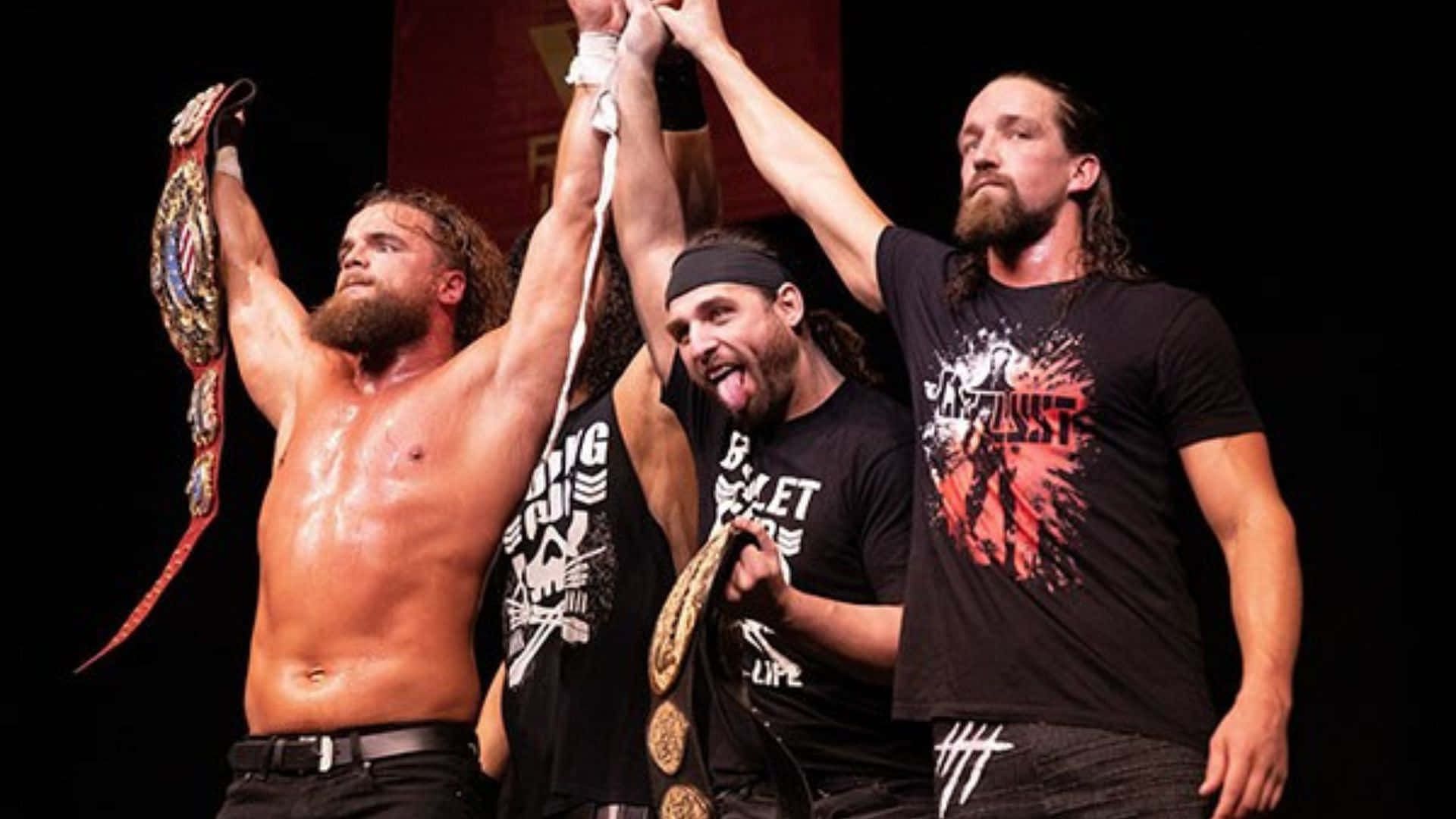 Juice Robinson IWGP美國冠軍 壁紙 — 三位肌肉發達的摔角手在舞台上高舉冠軍腰帶，在明亮燈光下慶祝勝利。