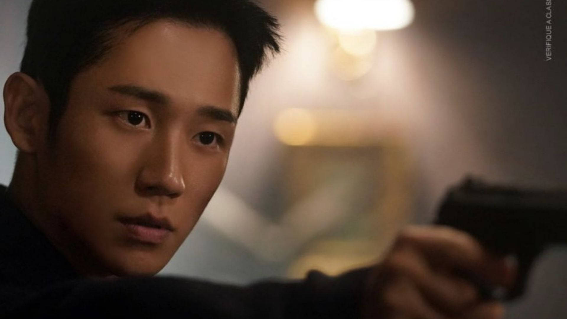 Jung Hae-In 在《雪滴花》劇中持槍對峙 壁紙 — 一個緊張的特寫鏡頭，一個男人在昏暗的房間裡專注地握著手槍。