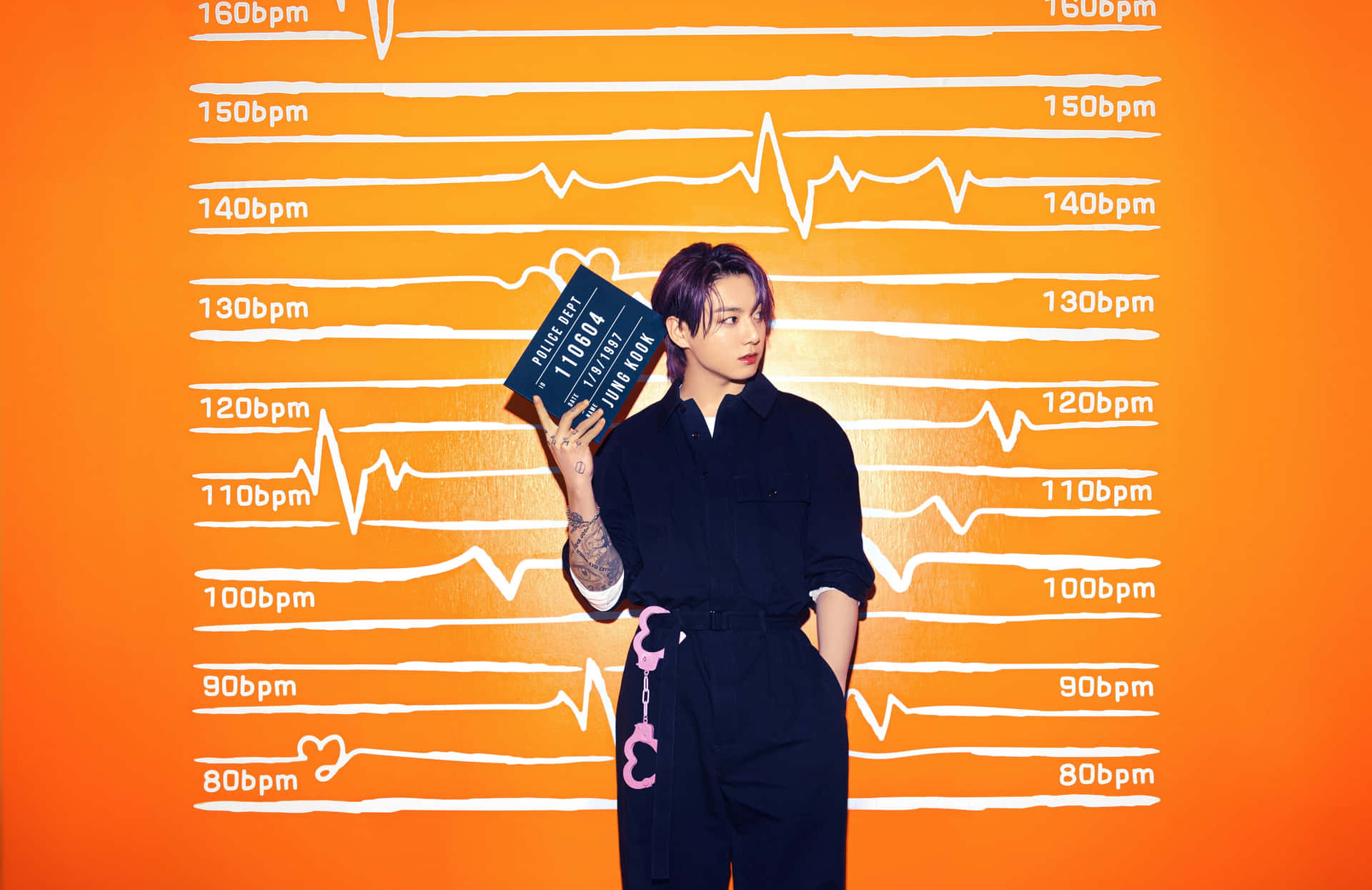 Jungkook 舞台熱情演出 壁紙 — 一名身穿深色衣服的人，在帶有白色心跳線圖案的鮮橙色牆前舉著拍板。