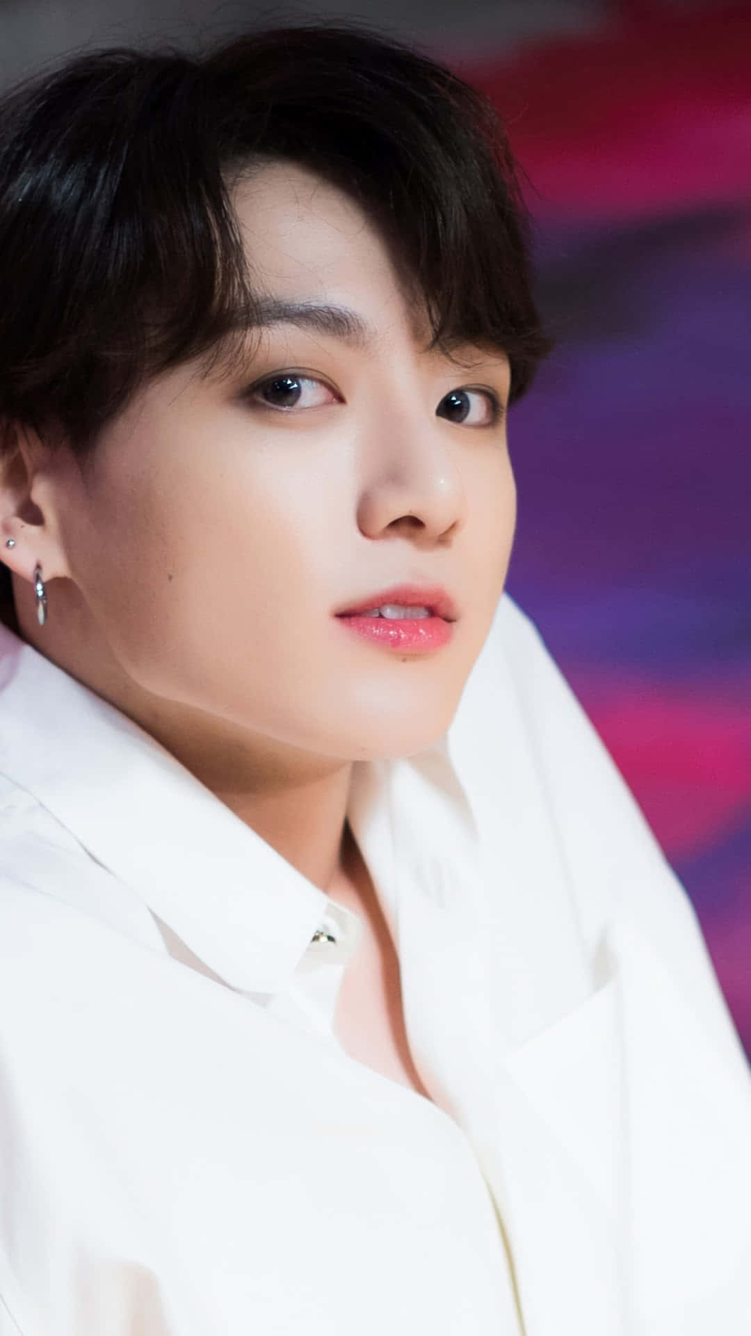 Jungkook在舞台上燃爆氣氛 壁紙 — 年輕黑髮白衫男子特寫肖像，背景為鮮豔的紫色和粉紅色模糊效果。
