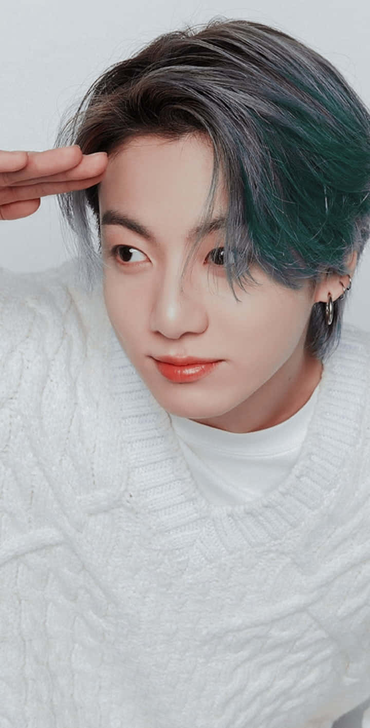 Jungkook於攝影棚展現迷人魅力 壁紙 — 一位年輕男子擁有引人注目的綠色和灰色頭髮，穿著白色針織毛衣，輕輕觸碰額頭。