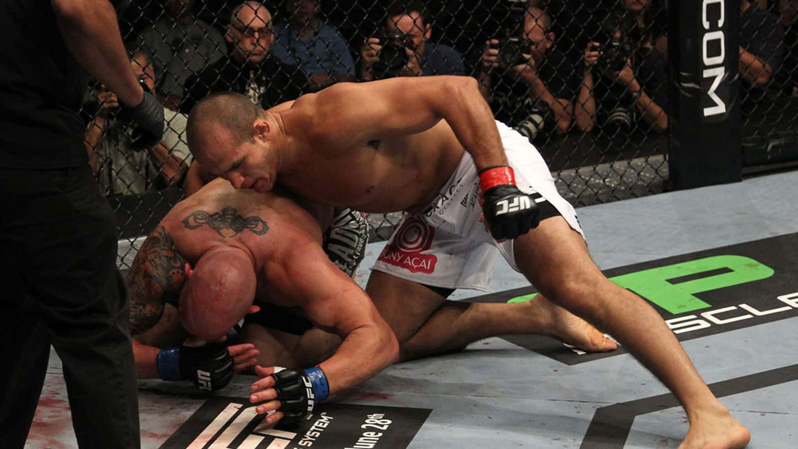 兩名MMA拳手在UFC八角籠內激烈纏鬥，墊上有血跡。