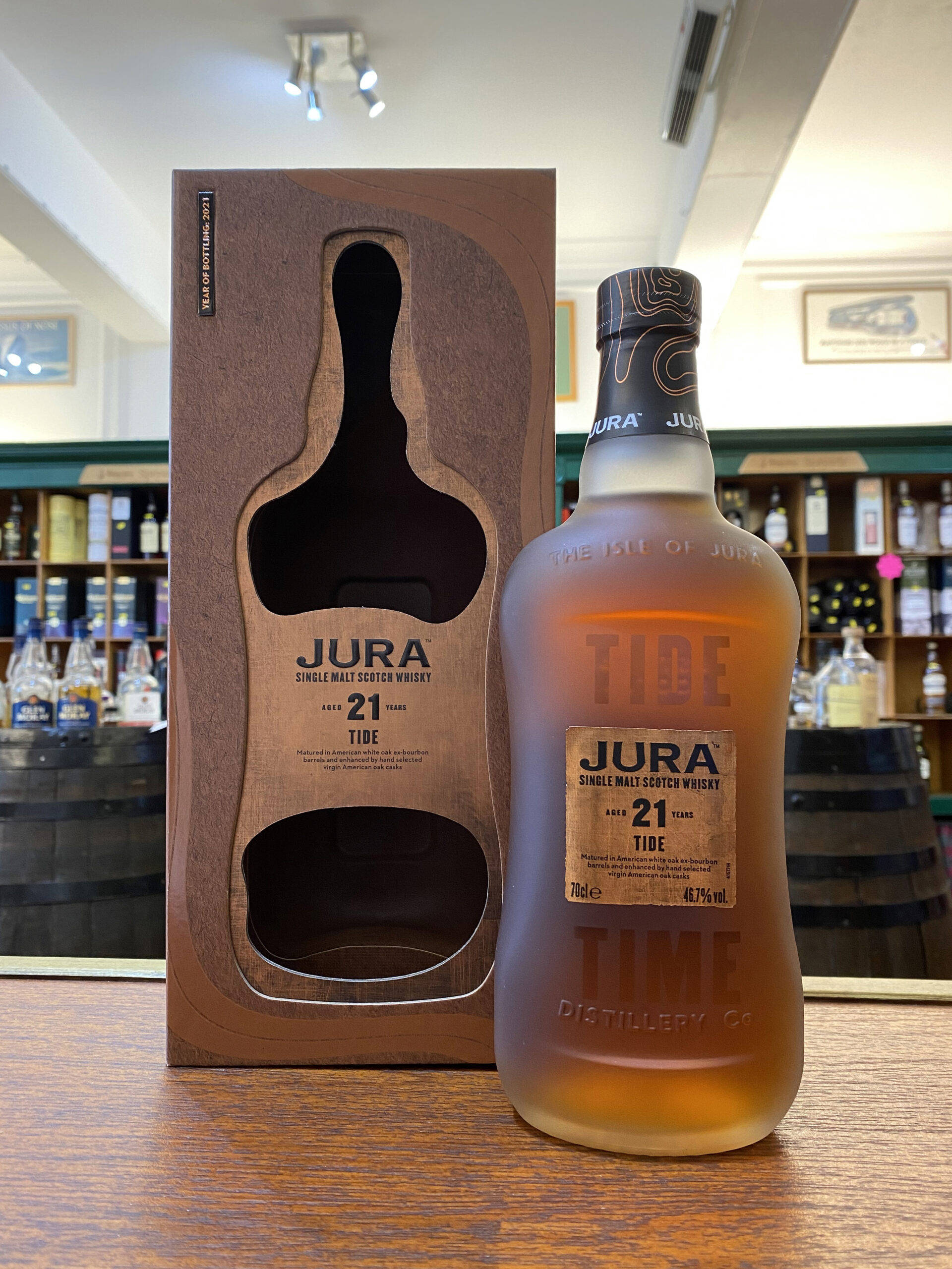 Jura 21年陳釀潮汐蘇格蘭威士忌 壁紙 — 一瓶Jura 21年單一麥芽蘇格蘭威士忌放在威士忌店的吧枱上，旁邊是其木製禮盒。