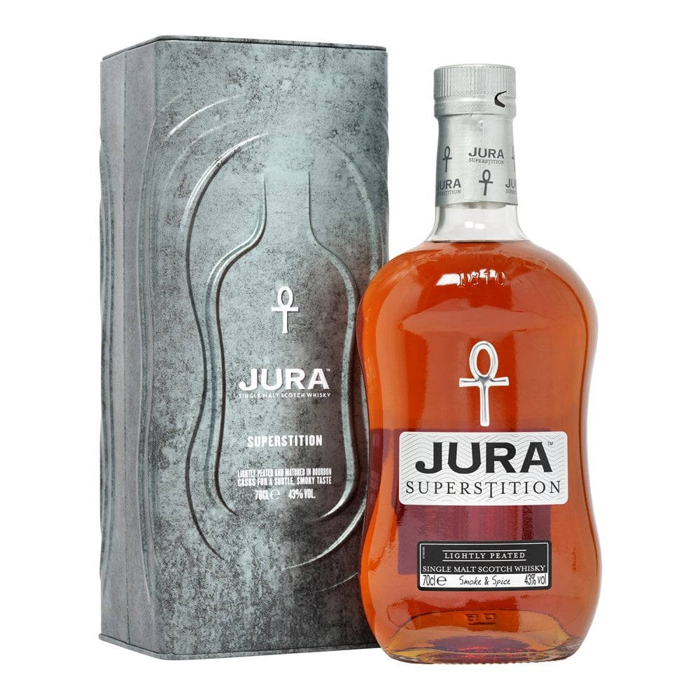 Jura蒸餾廠公司出品酒品 壁紙 — 一瓶Jura Superstition單一麥芽威士忌，琥珀色液體，旁邊是帶紋理的銀色包裝，背景為白色。