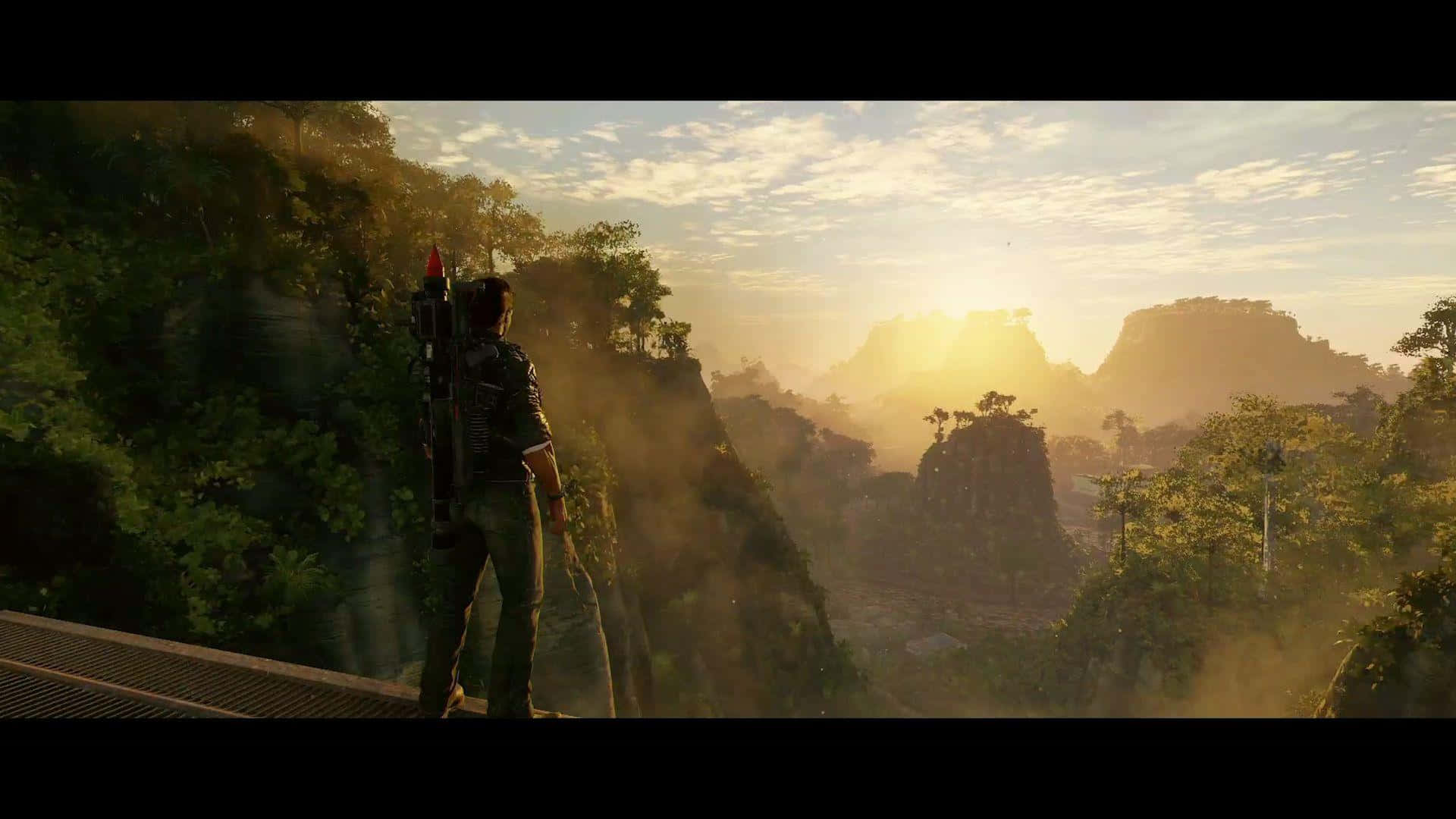 《Just Cause 4》最佳背景：里科欣賞日出 壁紙 — 一位孤獨的冒險家站在懸崖邊，在日出時俯瞰沐浴在金色光芒中的霧氣繚繞的叢林山脈。